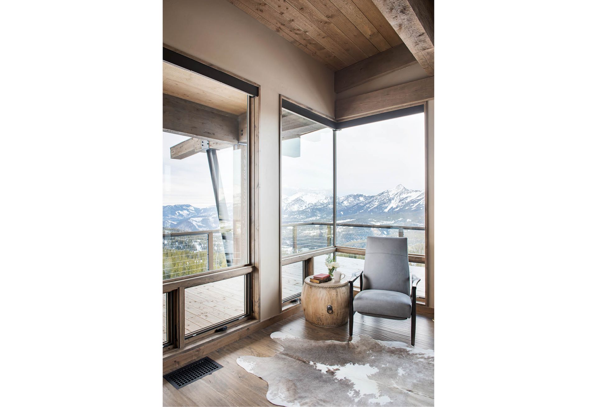 There is a chair in the corner of the room with a view of the mountains.