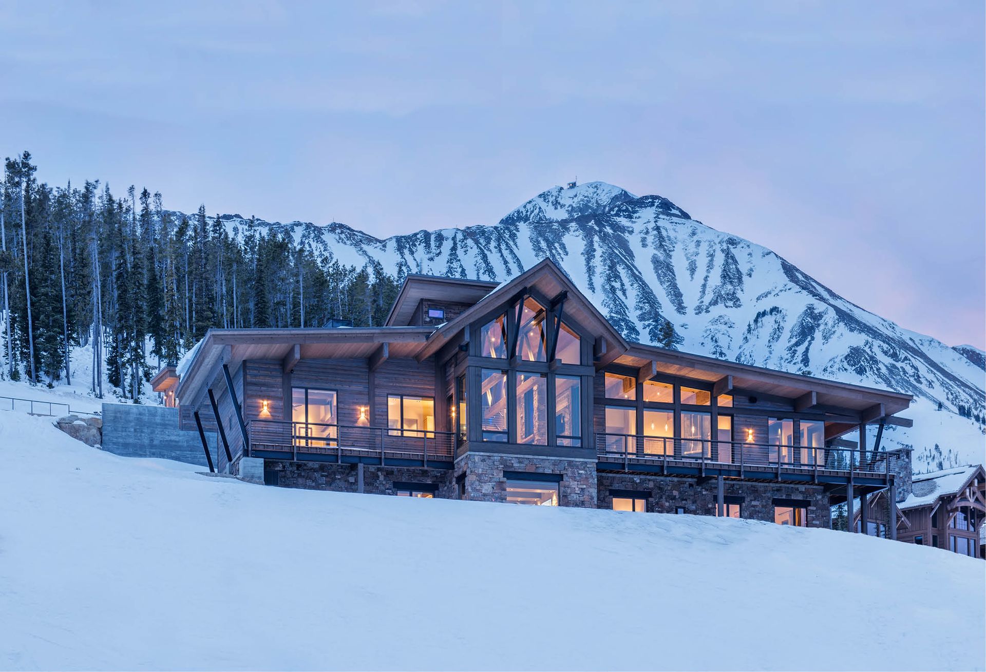 A large house is sitting on top of a snow covered hill.