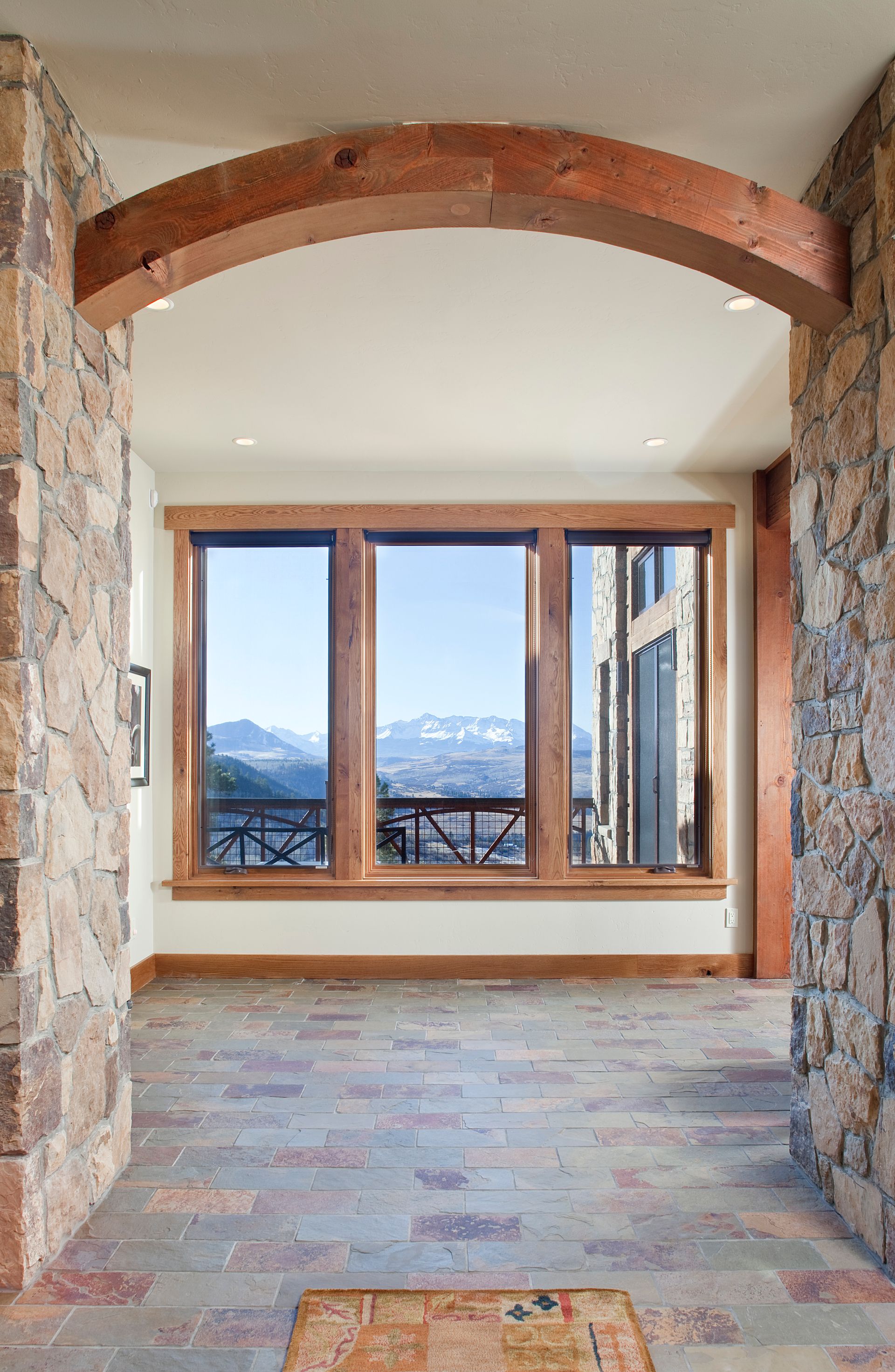 A hallway with a large window and a stone wall
