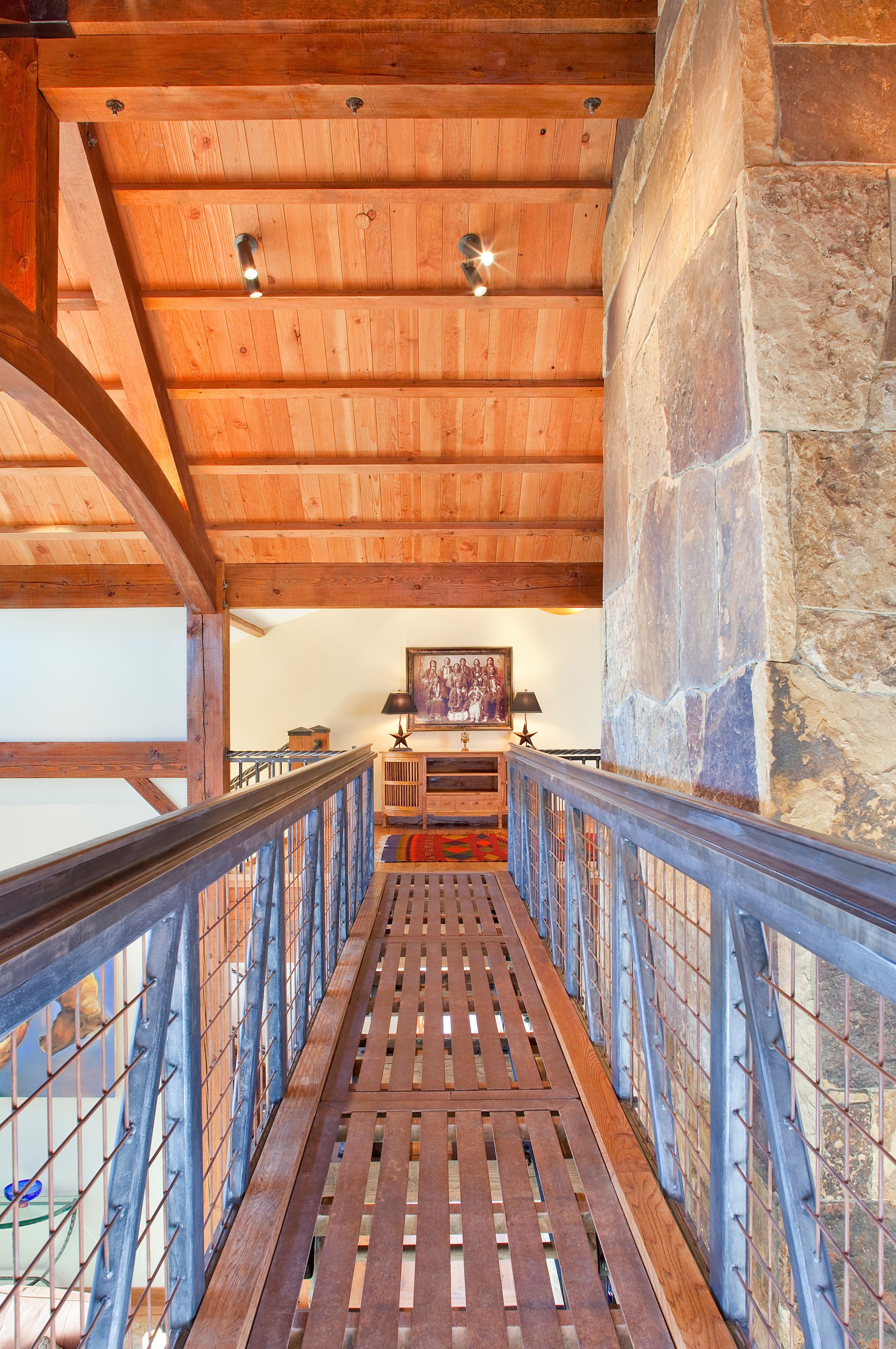 A wooden walkway with a metal railing leading to a living room.