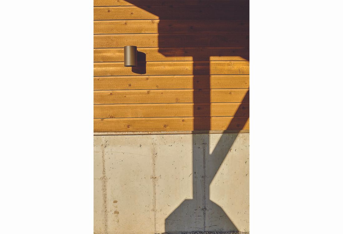 A shadow of a pole is cast on a wooden wall.