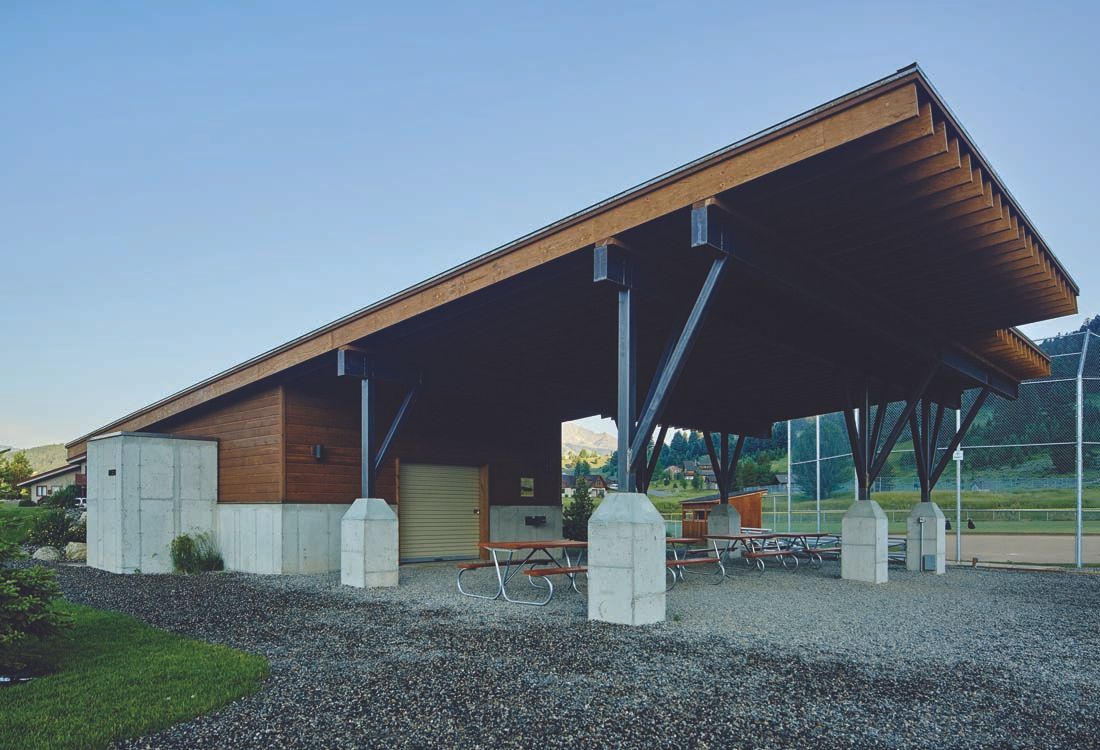 A small building with a wooden roof and a picnic table underneath it