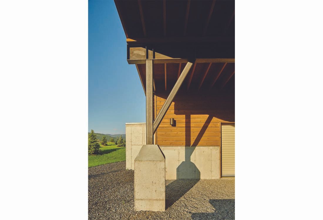 A wooden house with a concrete pillar in front of it.