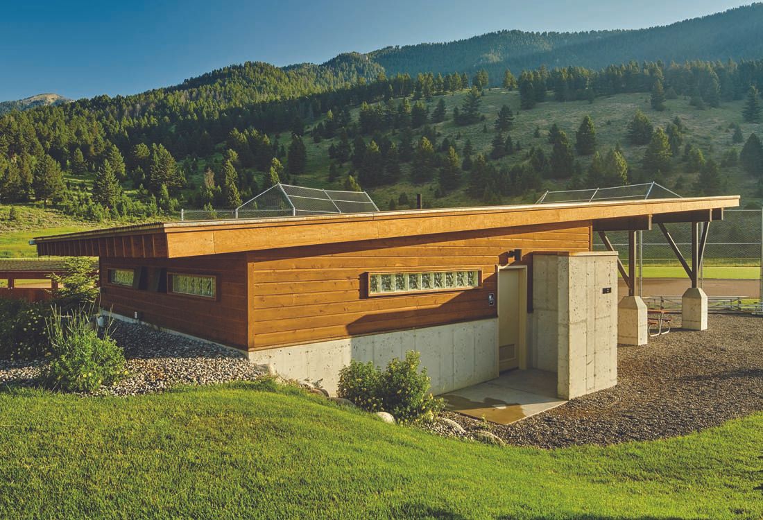 A small wooden house is sitting on top of a lush green hillside.