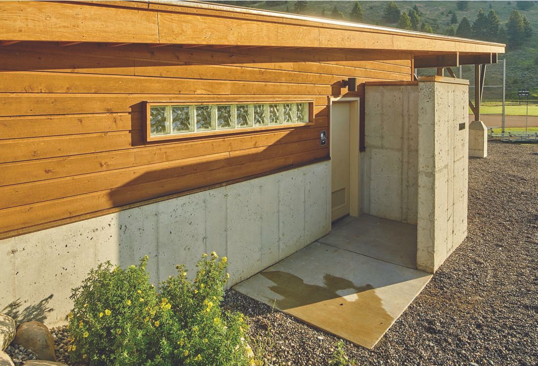A wooden building with a concrete wall and a door