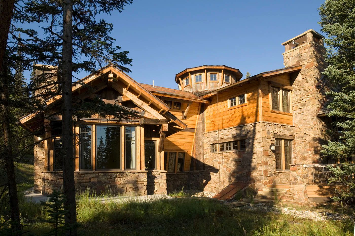 A large wooden and stone house in the middle of a forest