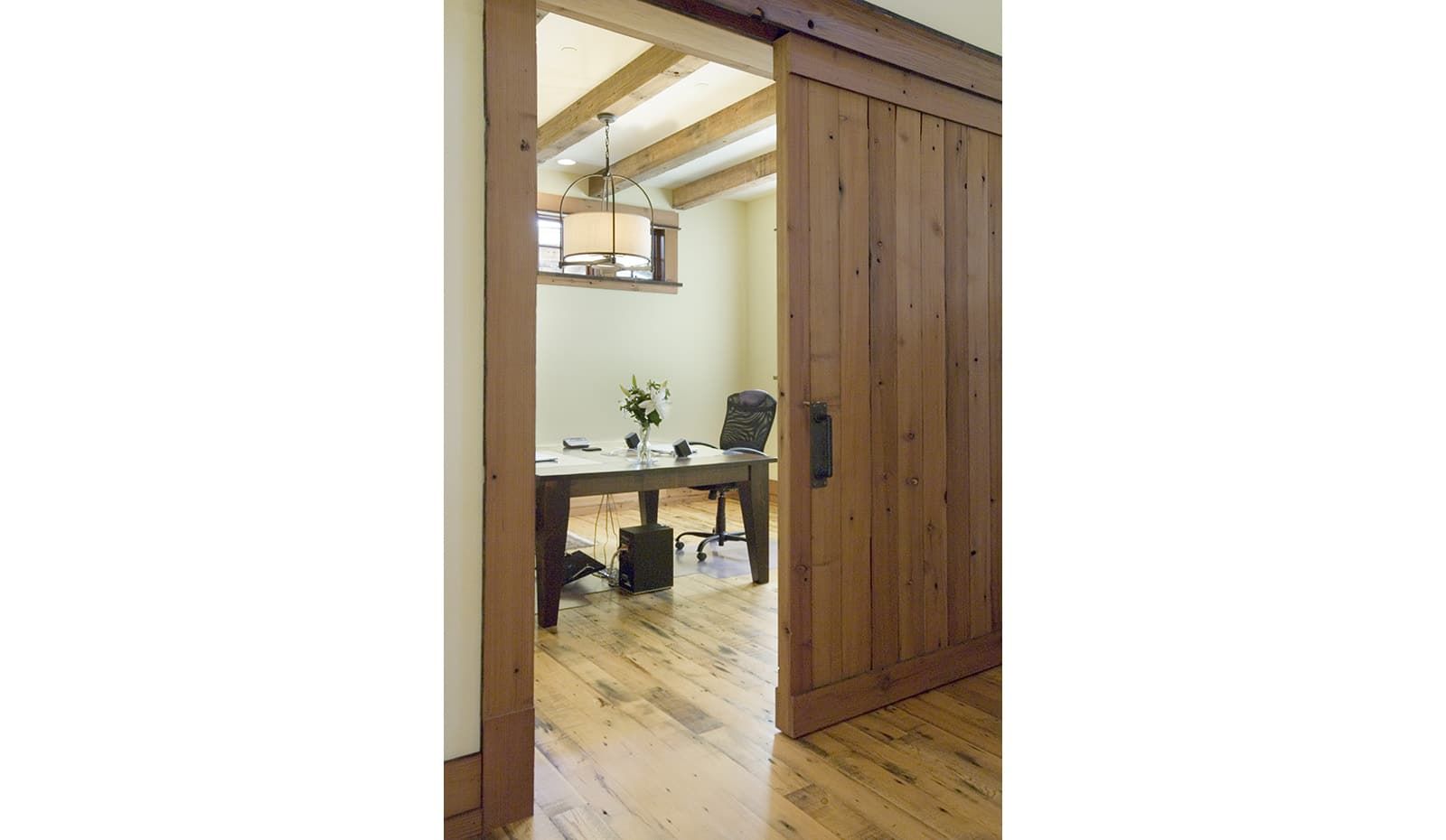 A sliding barn door opens to a room with a desk and chairs.