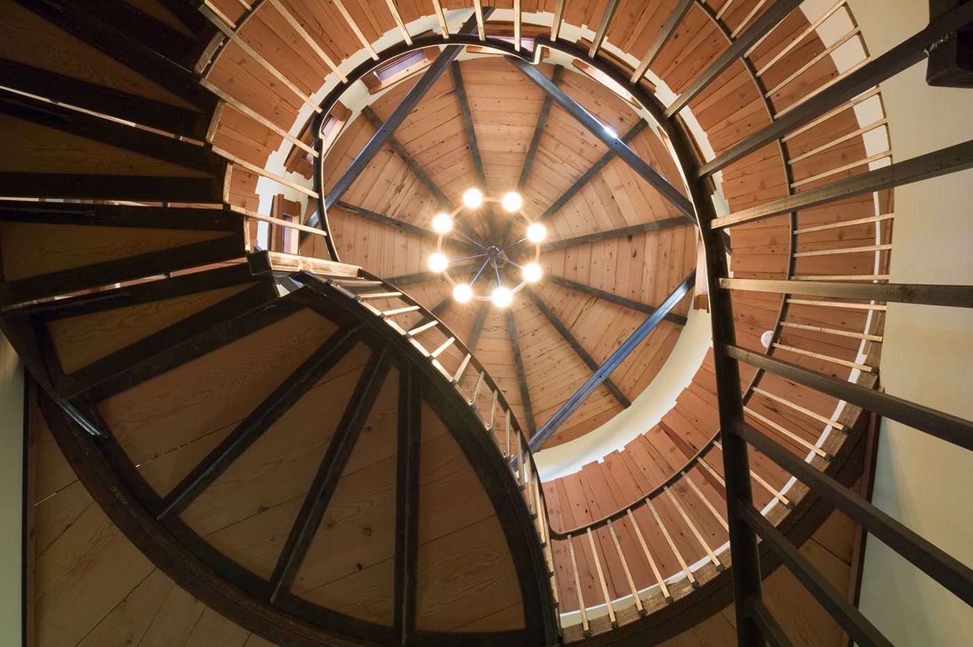 Looking up at a spiral staircase with a chandelier hanging from the ceiling