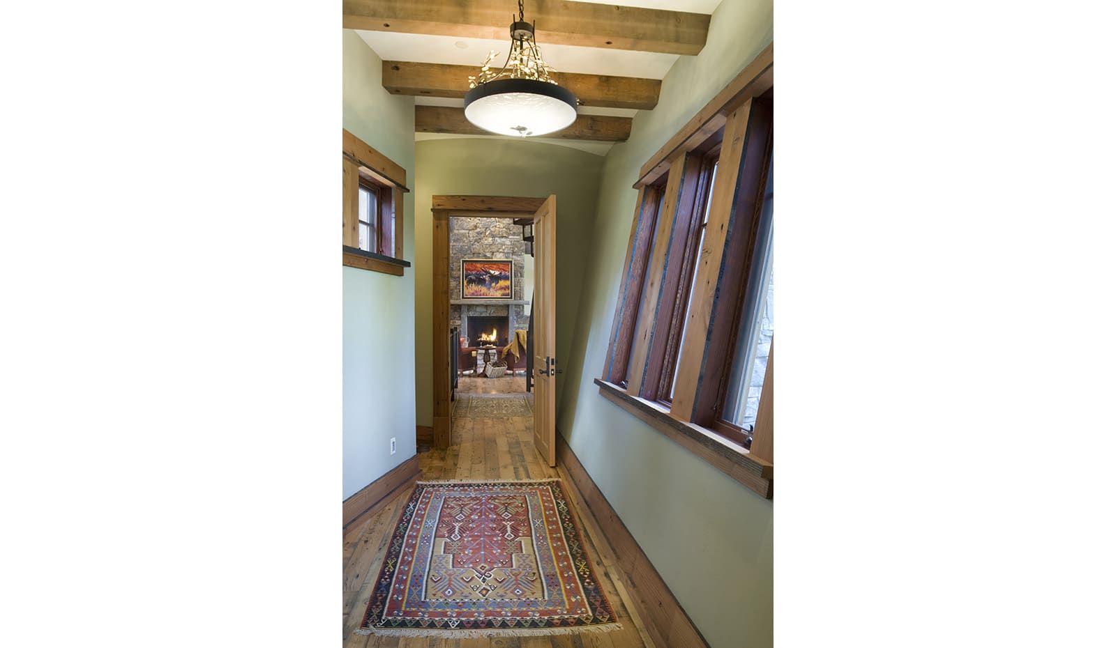 A hallway with a rug on the floor and a chandelier hanging from the ceiling.