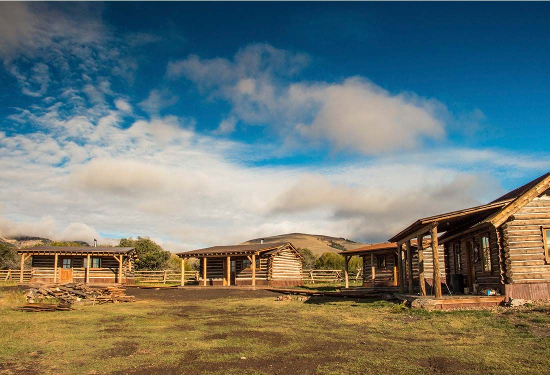 A log cabin is sitting in the middle of a grassy field.