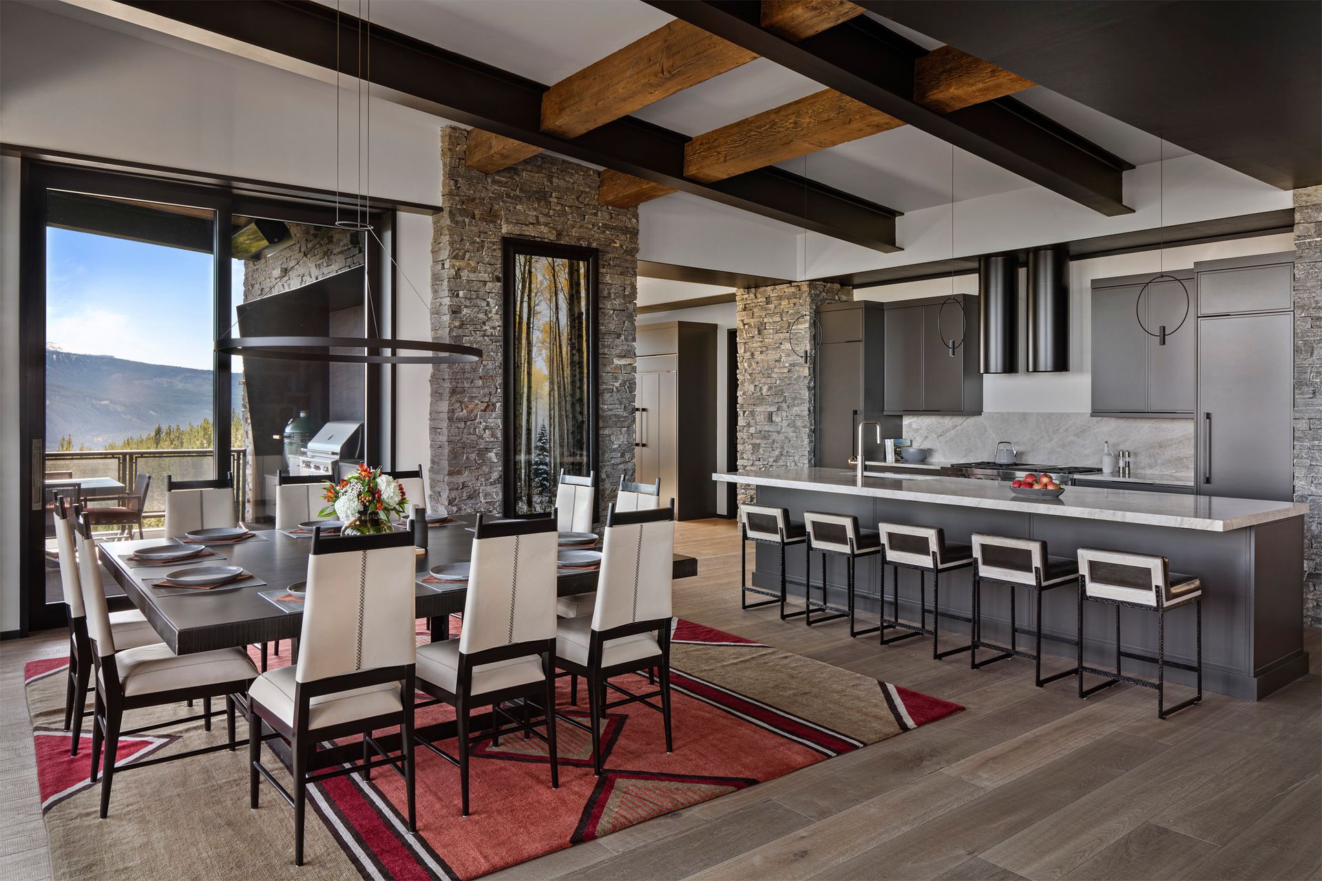 A dining room with a long table and chairs and a kitchen.