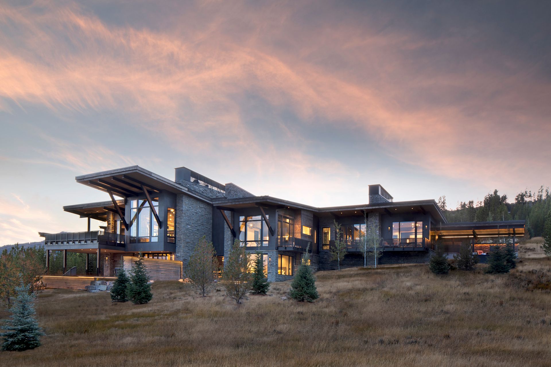 A large house is sitting on top of a dry grassy hill.