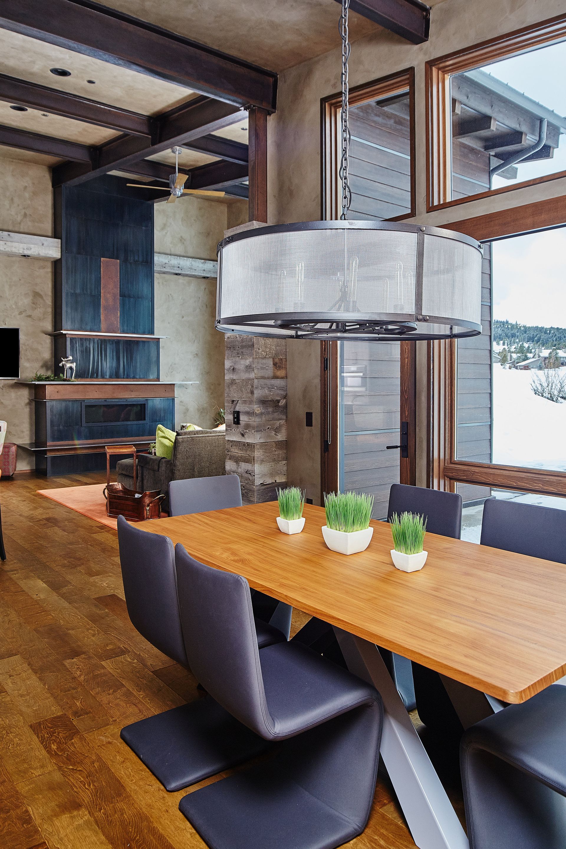 A dining room with a wooden table and chairs and a chandelier hanging from the ceiling.