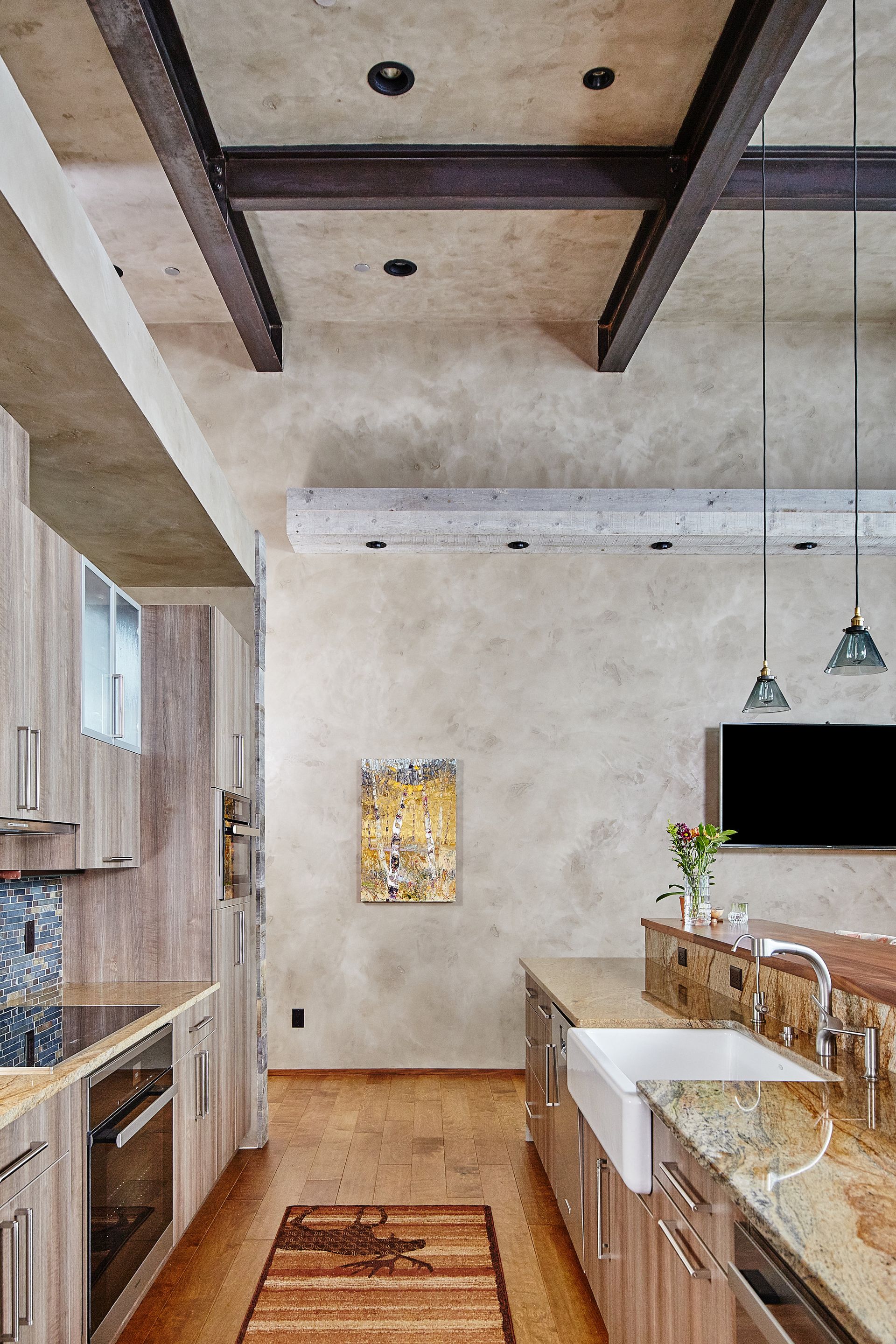 A kitchen with wooden cabinets , granite counter tops , a sink and a television.