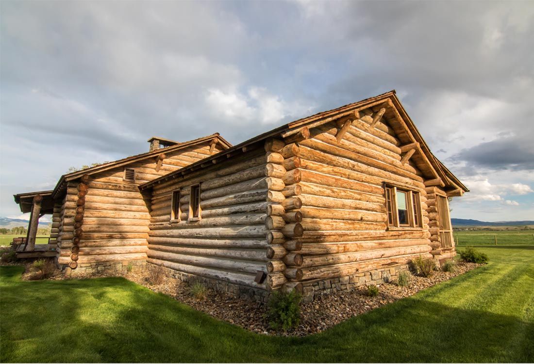 A log cabin is sitting in the middle of a grassy field.