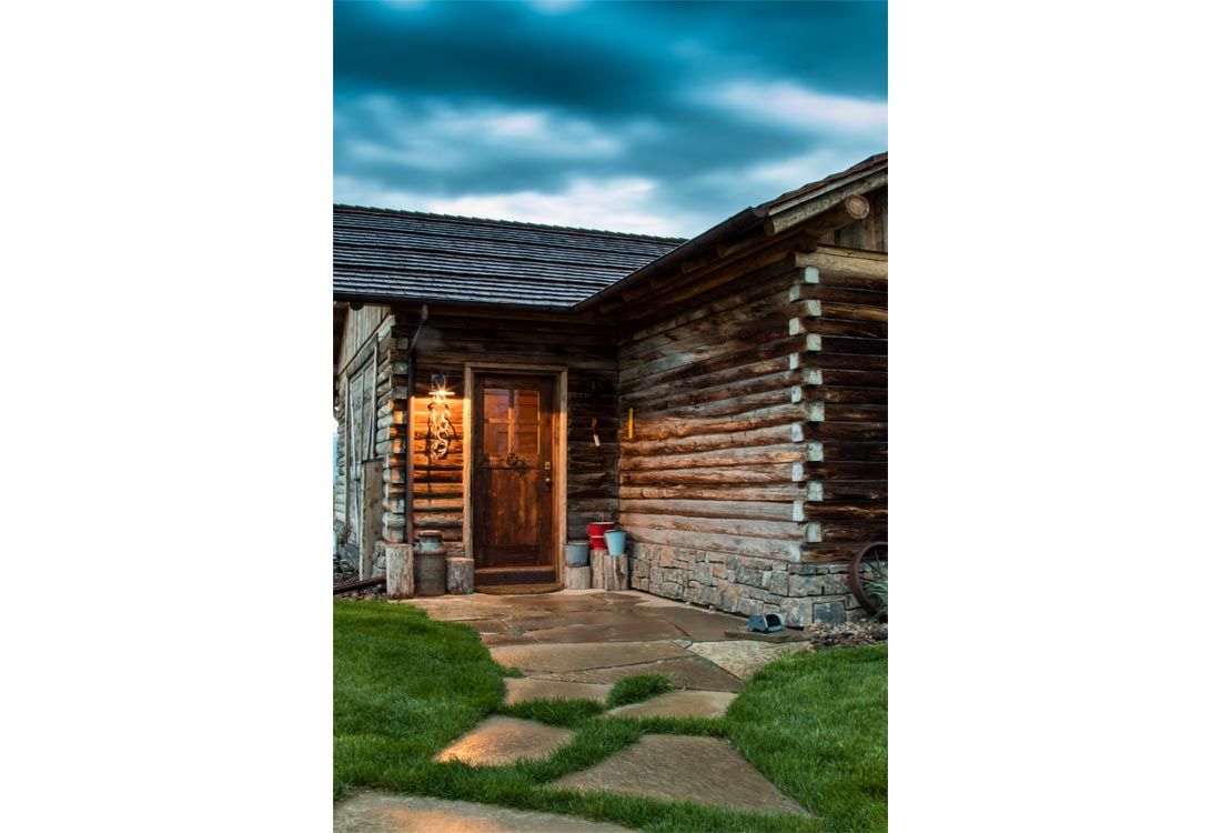A wooden cabin with a stone walkway leading to the door.