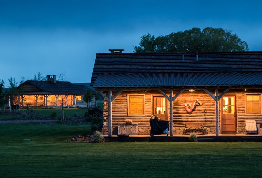 A log cabin with a porch is lit up at night.