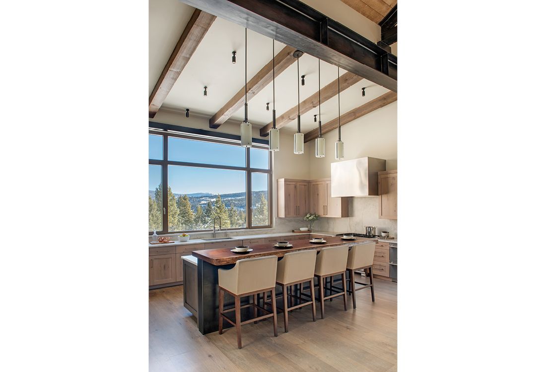 A kitchen with a large island and lots of windows.