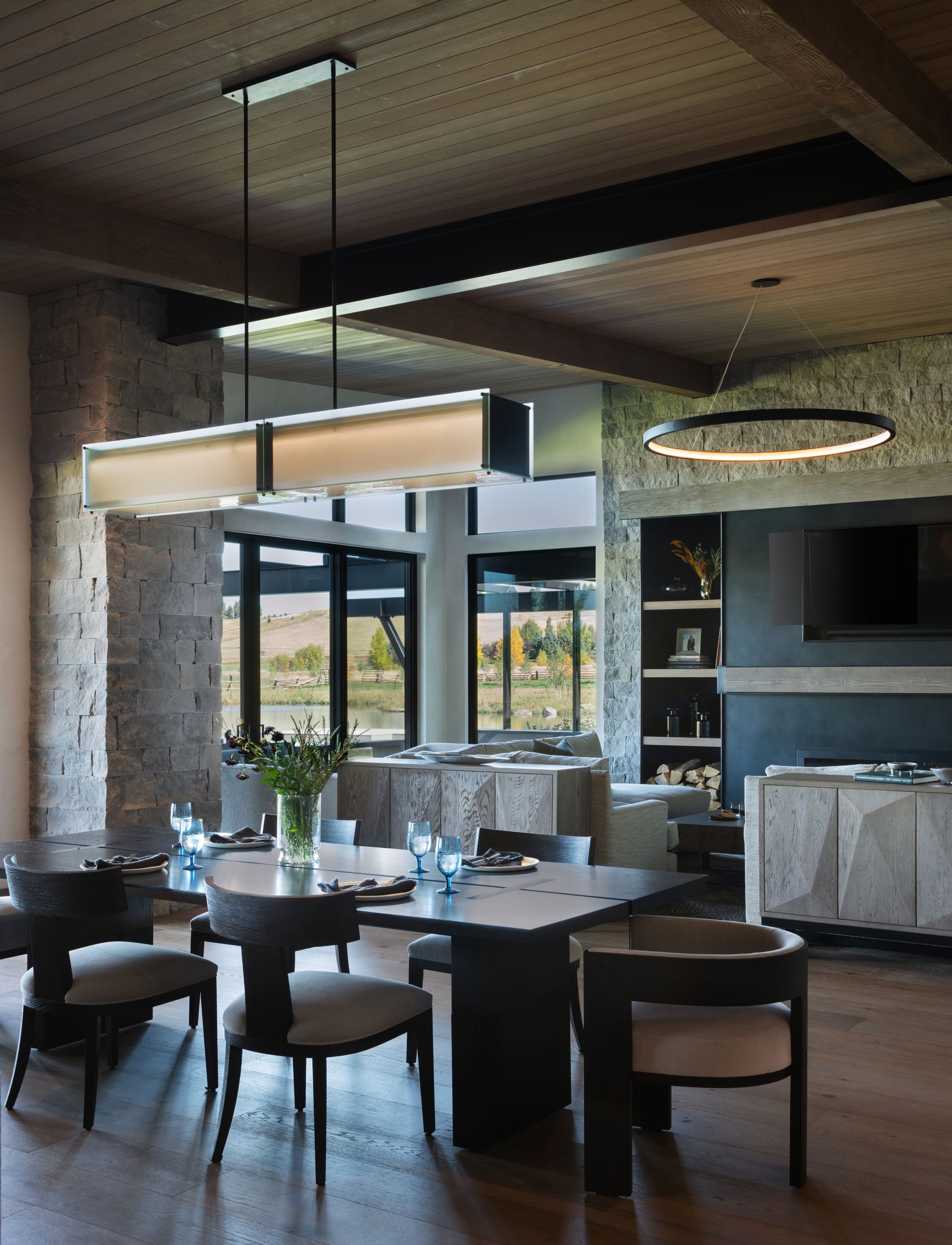 A dining room with tables and chairs and a large light hanging from the ceiling