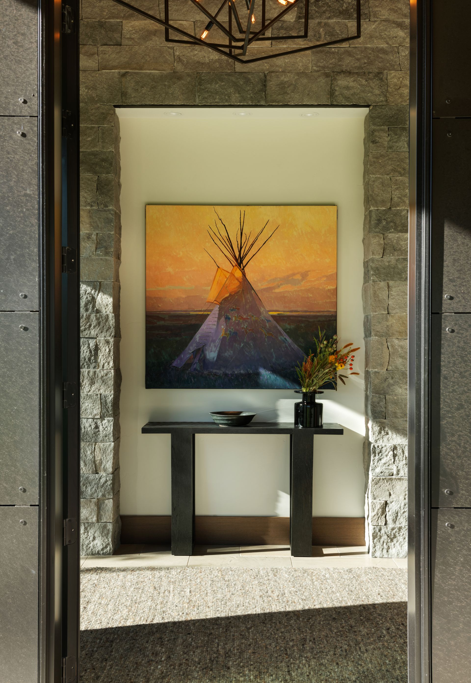 A painting of a teepee is hanging on a wall above a table