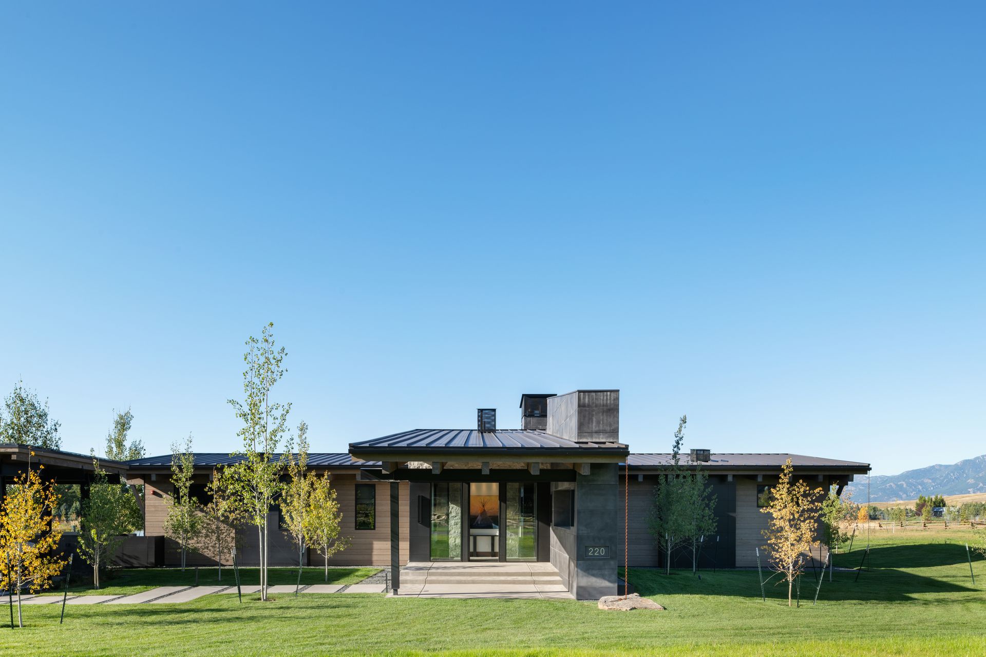 A large house is sitting in the middle of a lush green field.