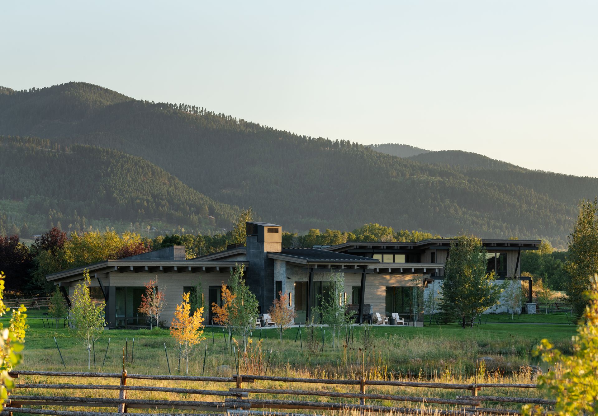 A large house in the middle of a field with mountains in the background
