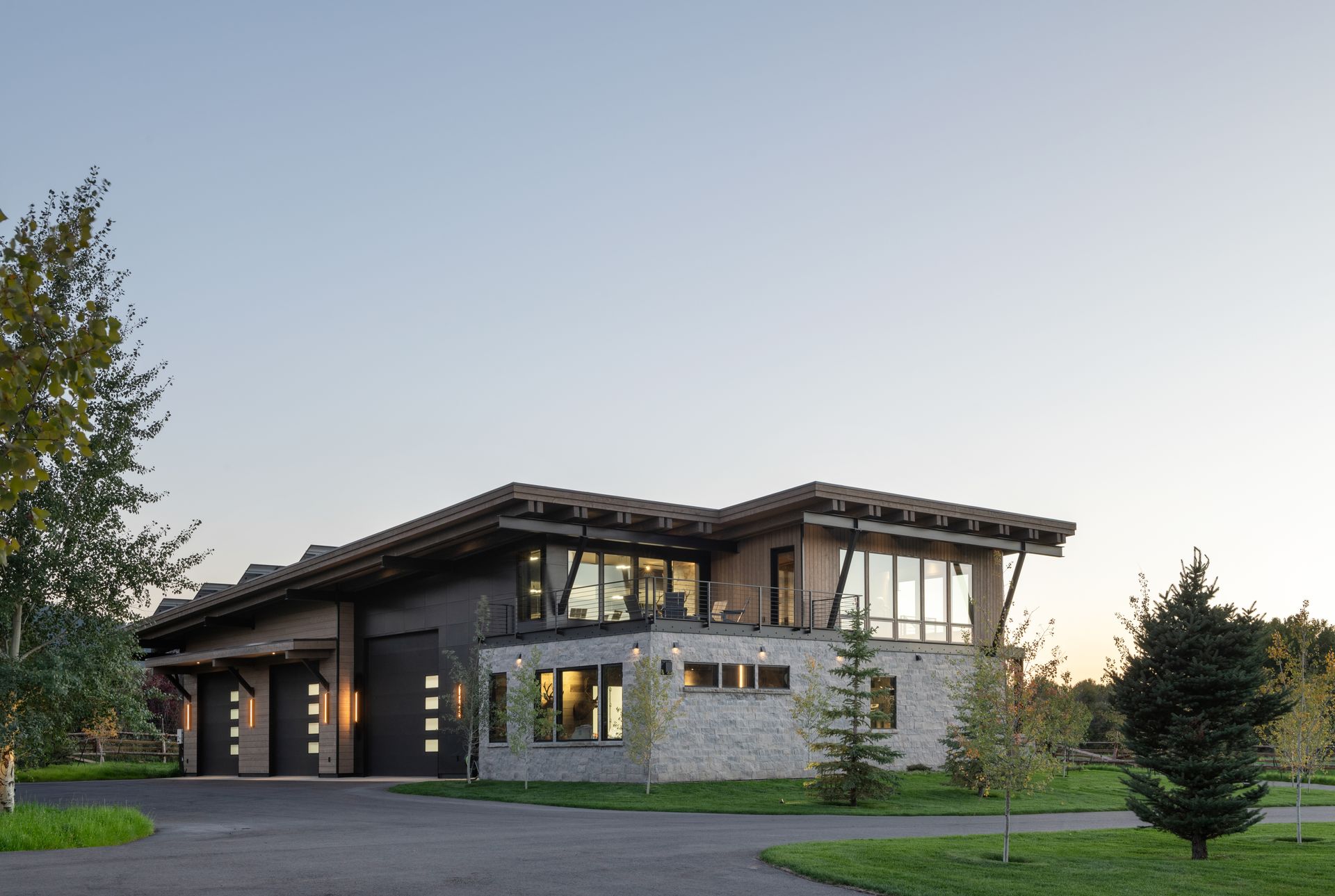 A large house with a lot of windows is sitting in the middle of a lush green field.