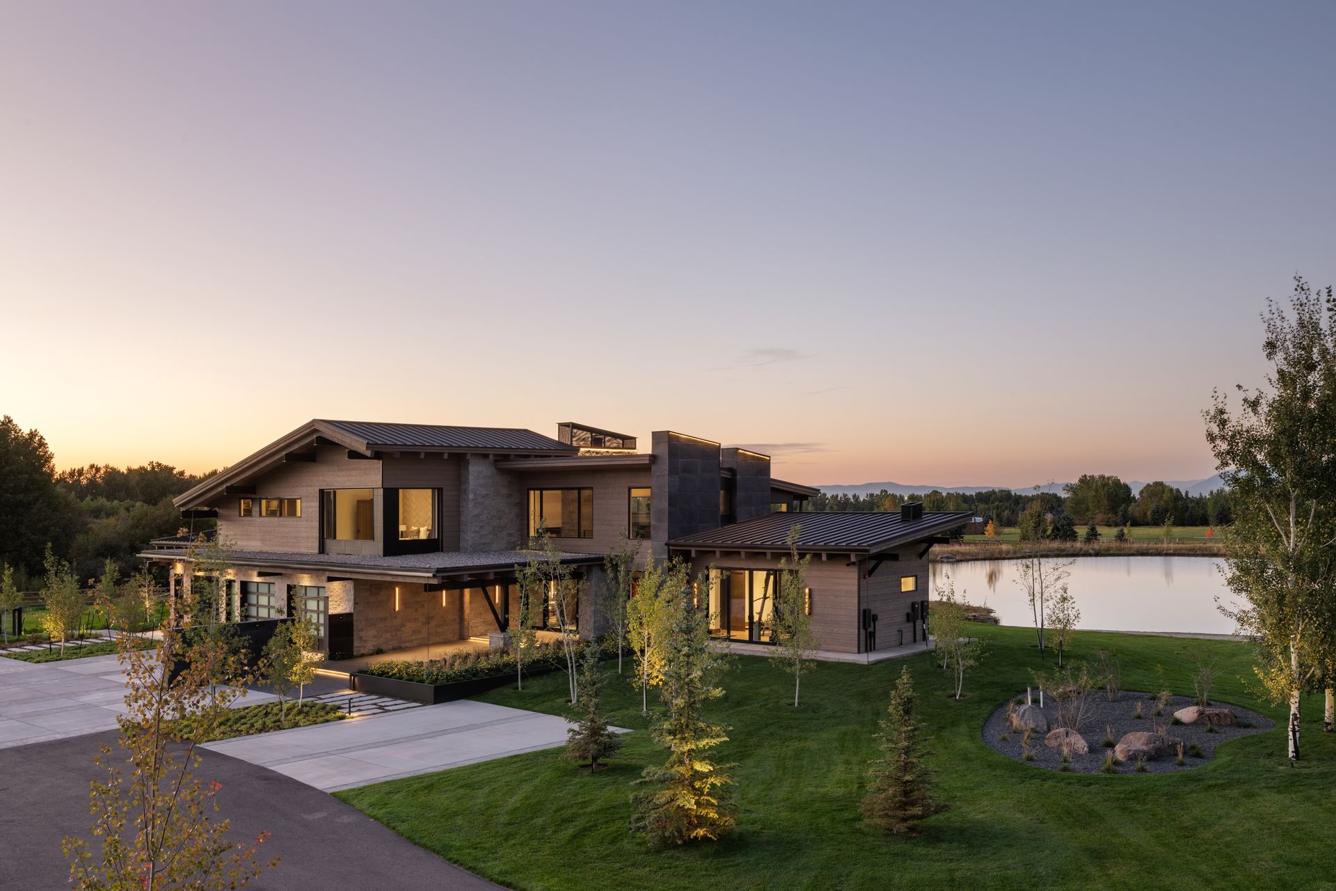 A large house is sitting next to a lake at sunset.