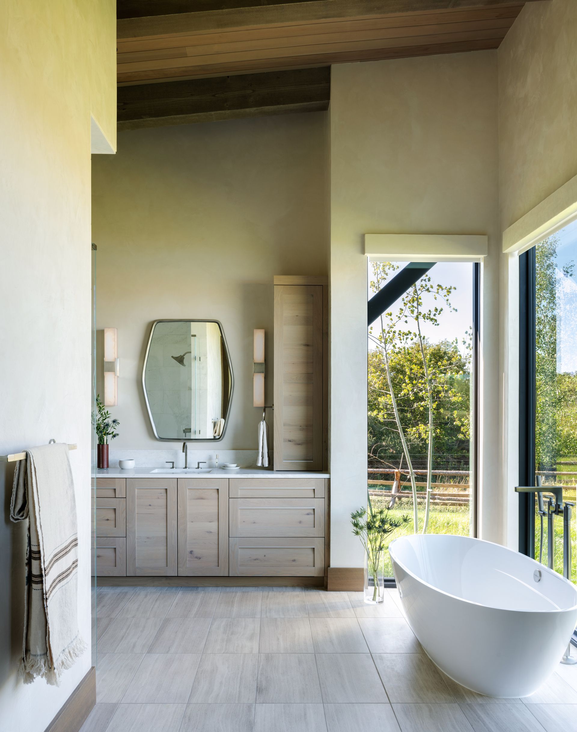 A bathroom with a tub , sink , mirror and window