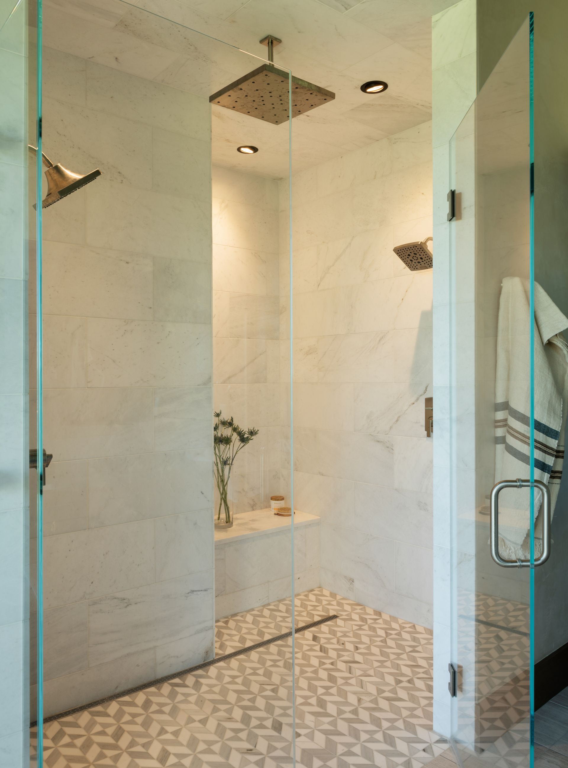 A bathroom with a walk in shower and a glass door