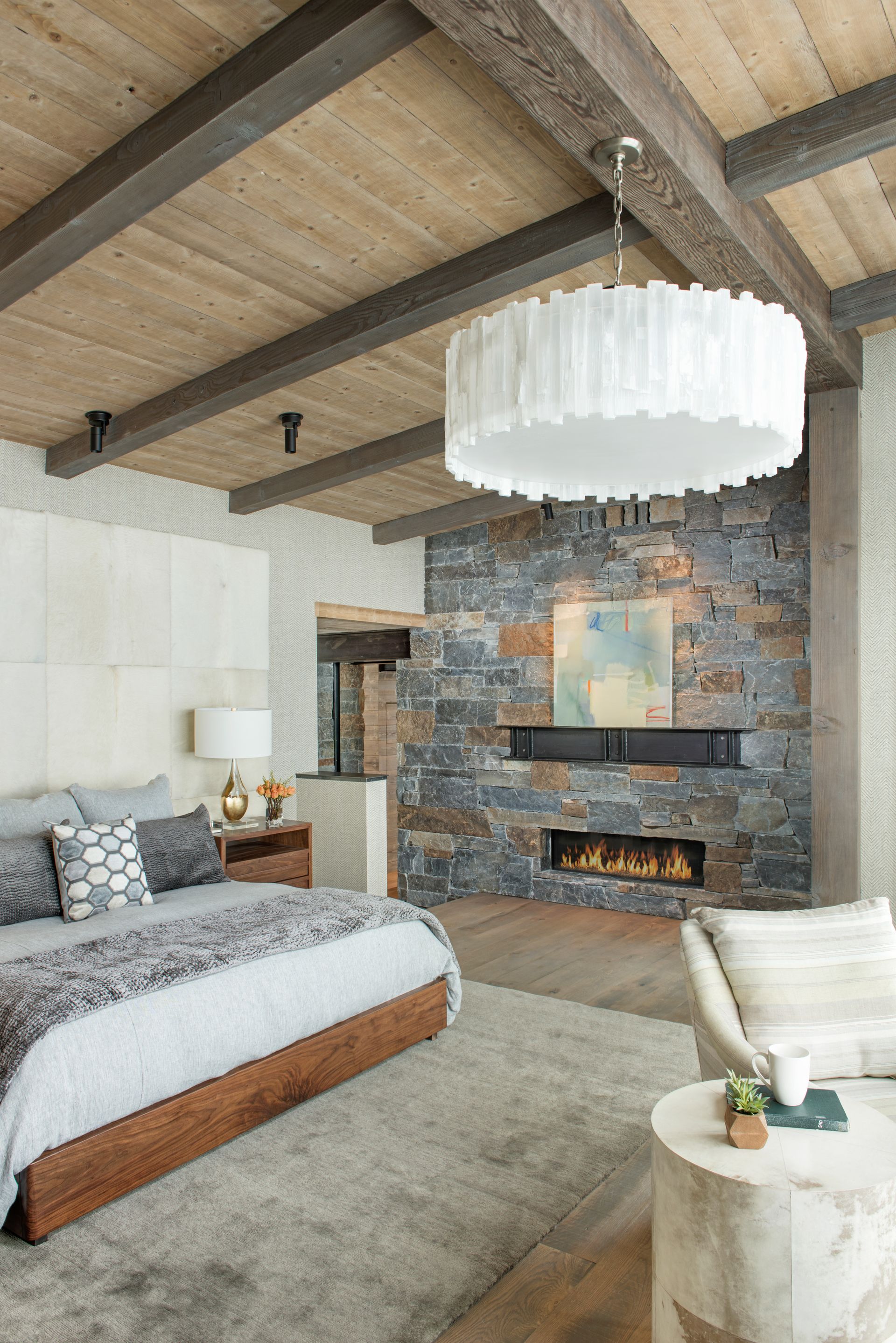 A bedroom with a bed , fireplace , and wooden beams.