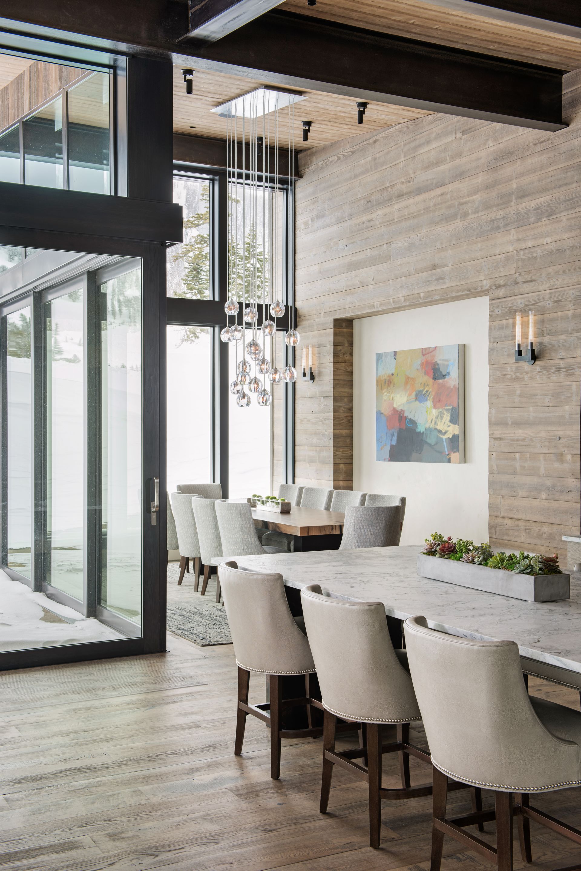 A dining room with a table and chairs and a painting on the wall.