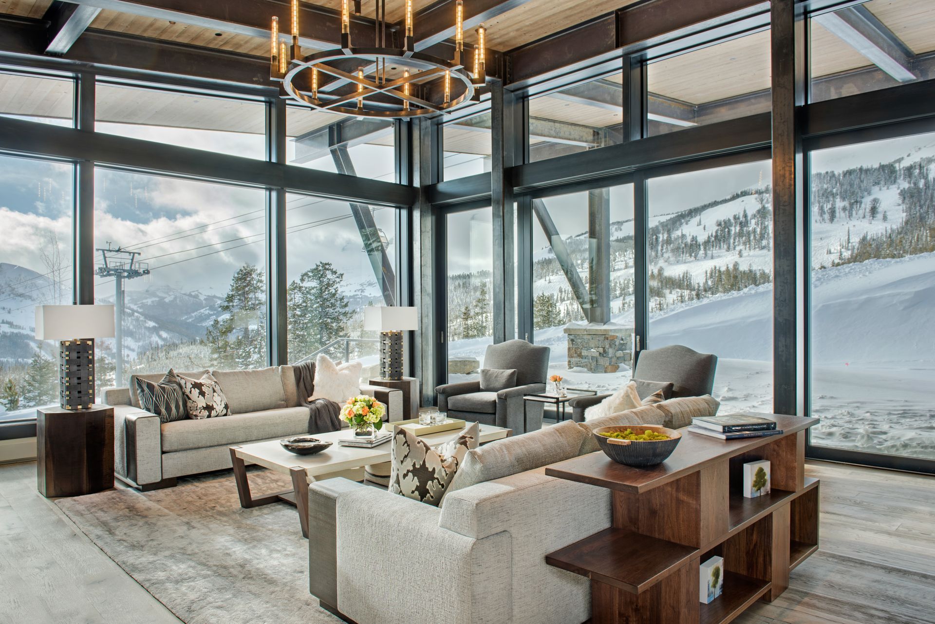 A living room with a lot of windows and a view of a snowy mountain.