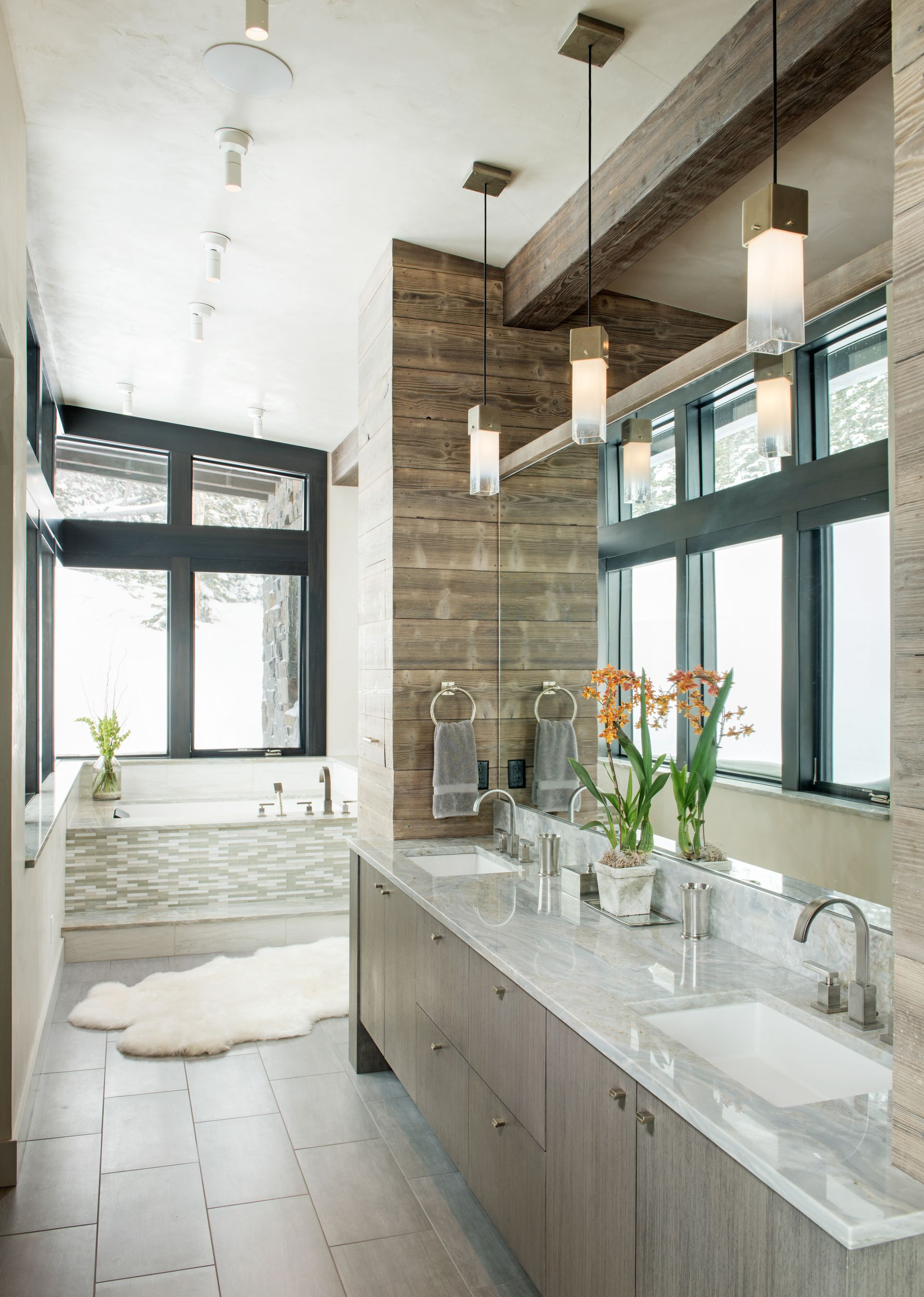 A bathroom with two sinks , a tub and a large mirror.