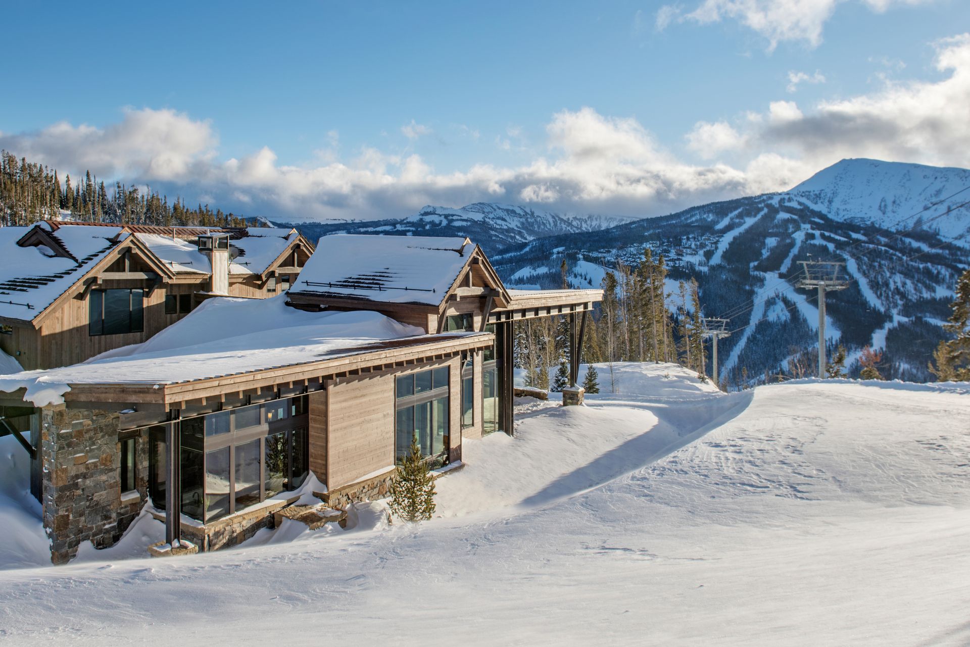 A large house is sitting on top of a snow covered hill.
