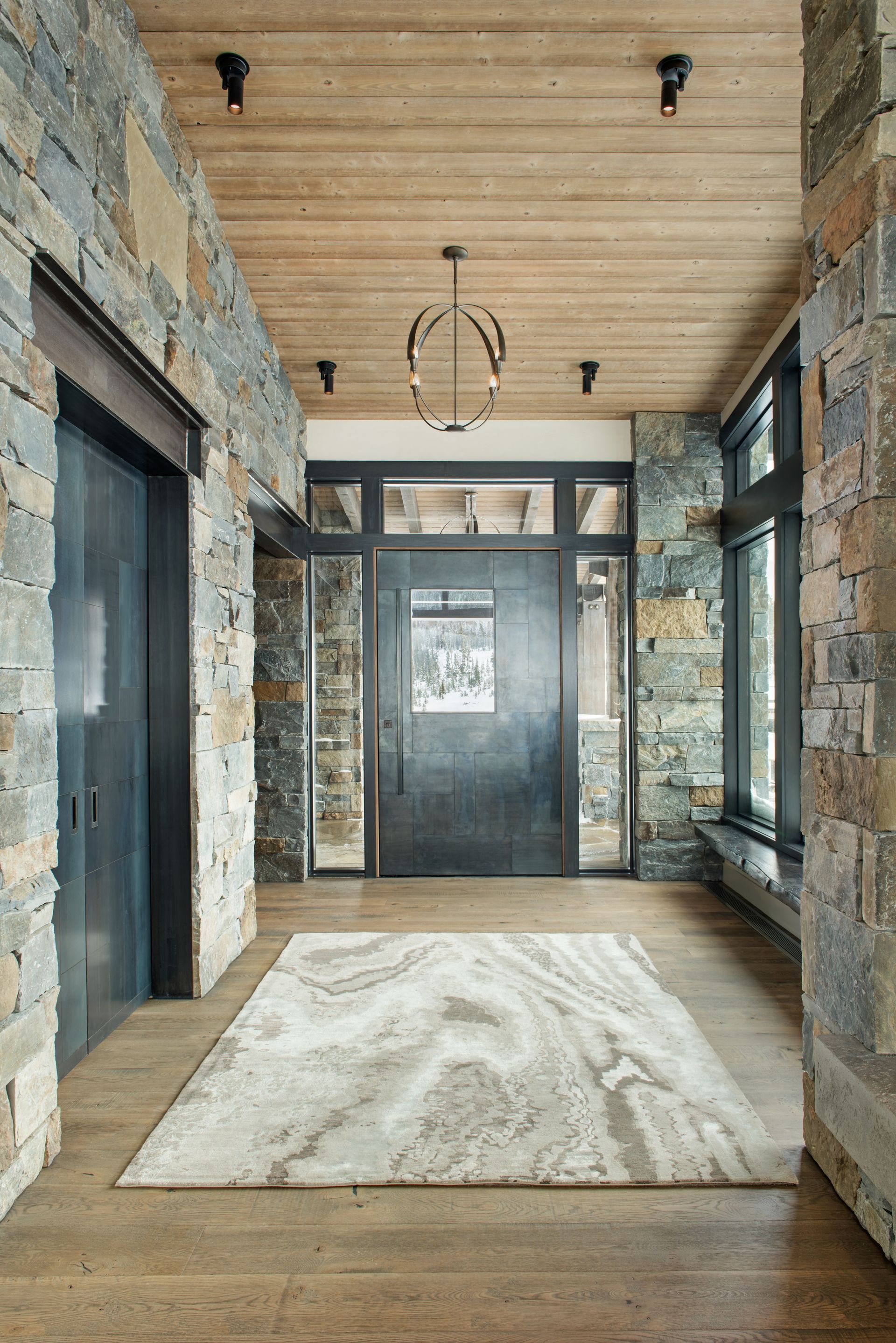 A hallway with a rug on the floor and a large door.