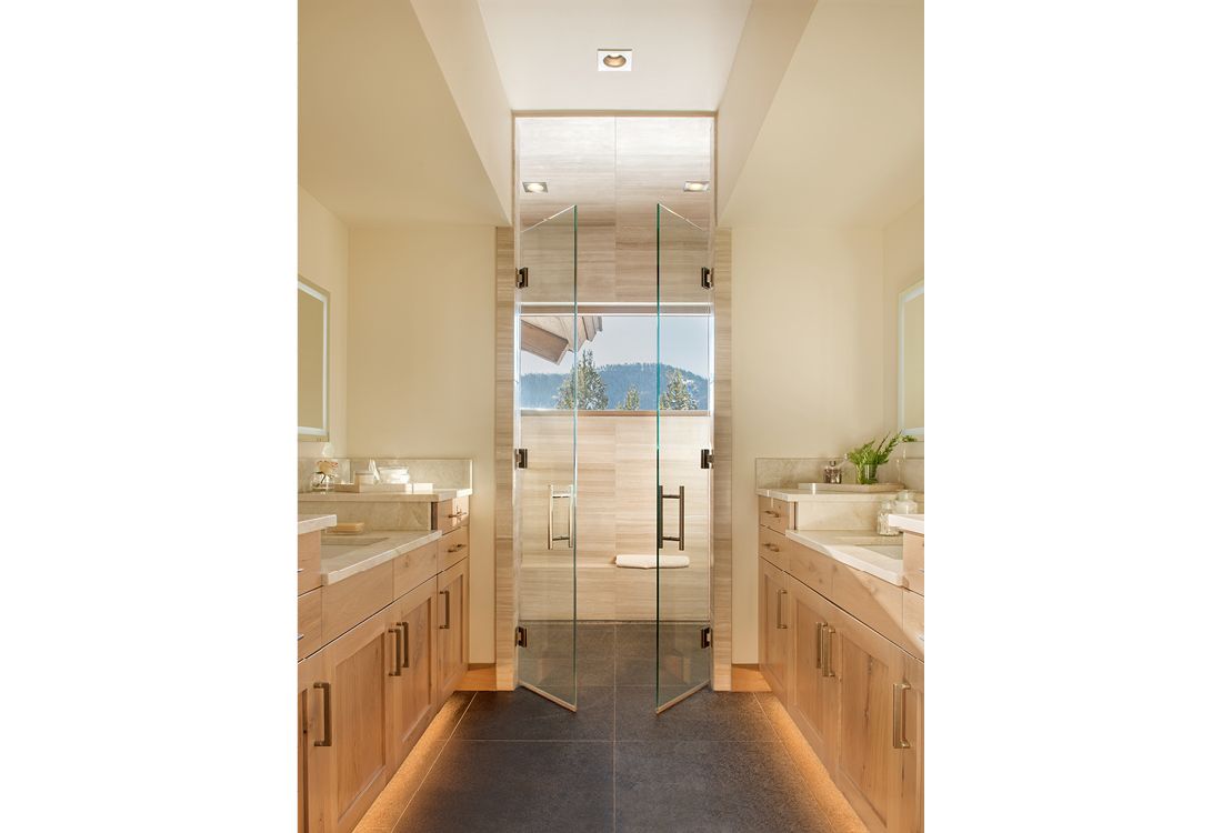 A bathroom with two sinks and a walk in shower.