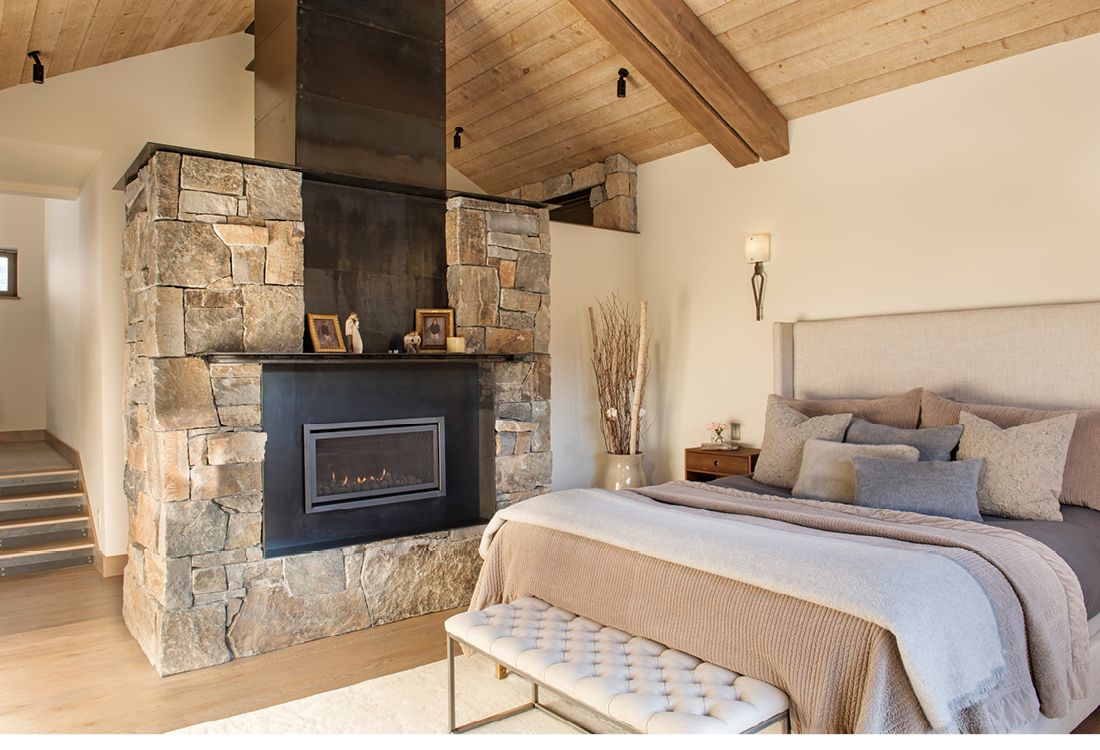 A bedroom with a large bed and a fireplace.