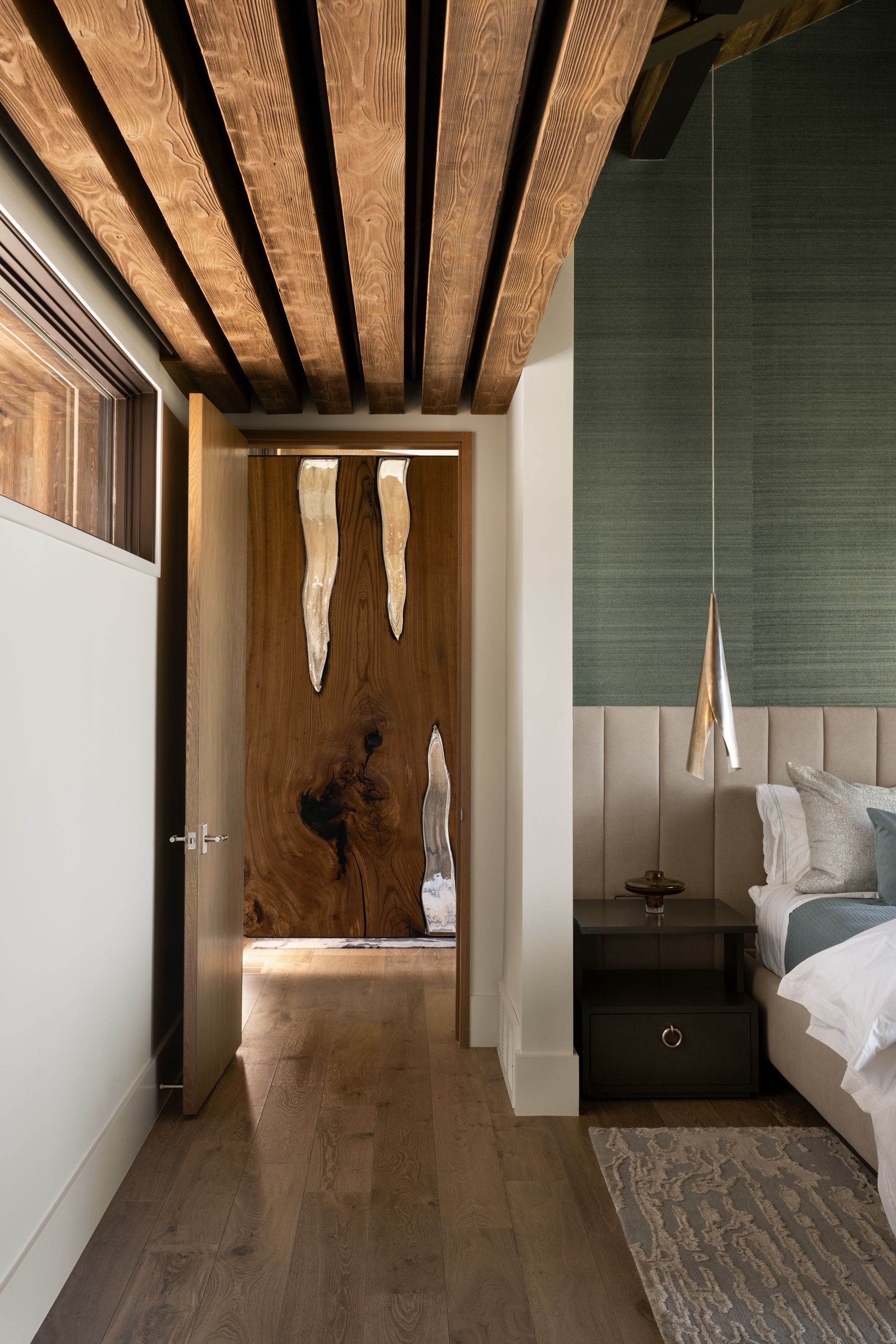 A bedroom with a bed , nightstand , and wooden beams on the ceiling.