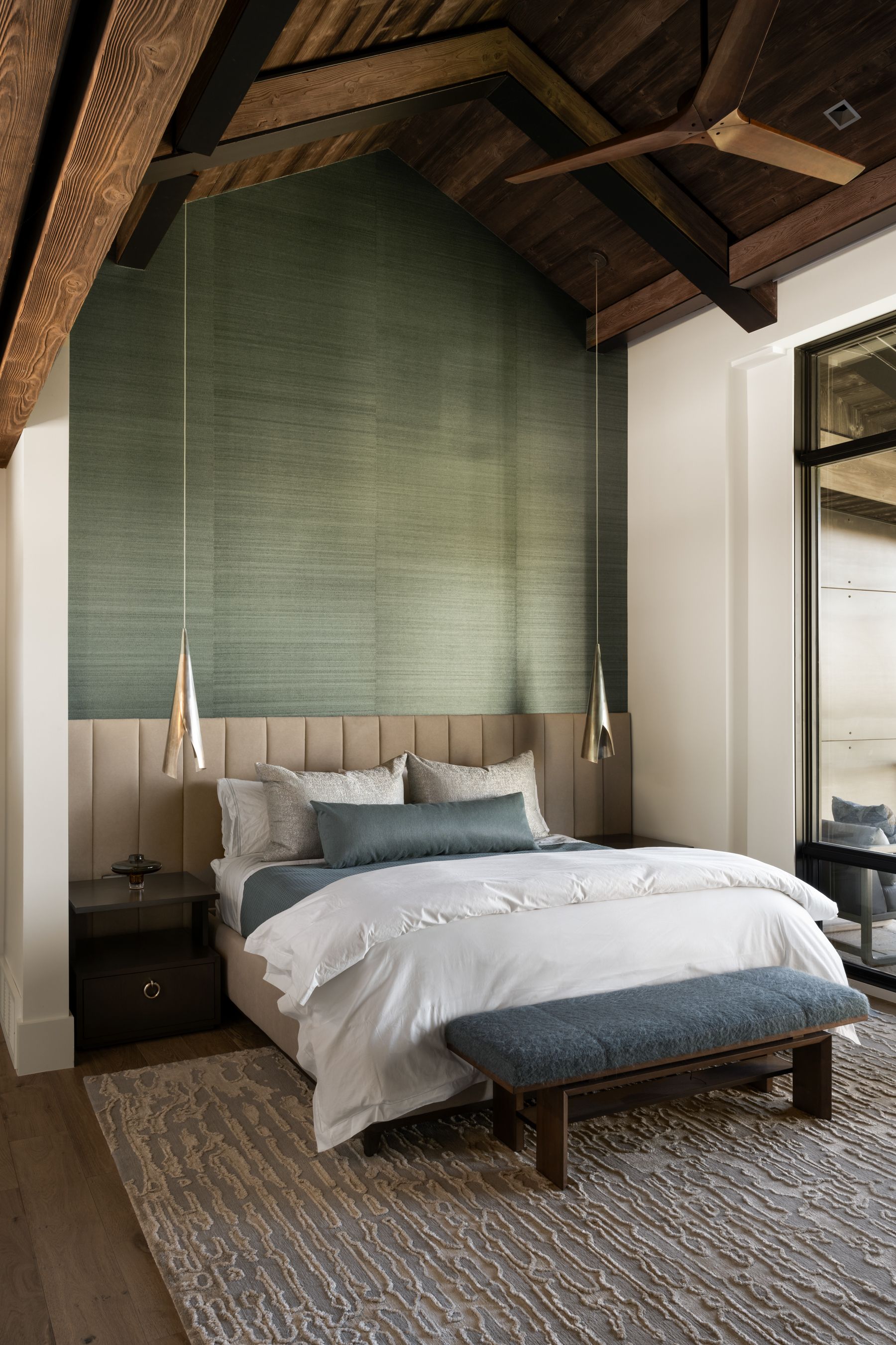 A bedroom with a bed , nightstand , bench and ceiling fan.