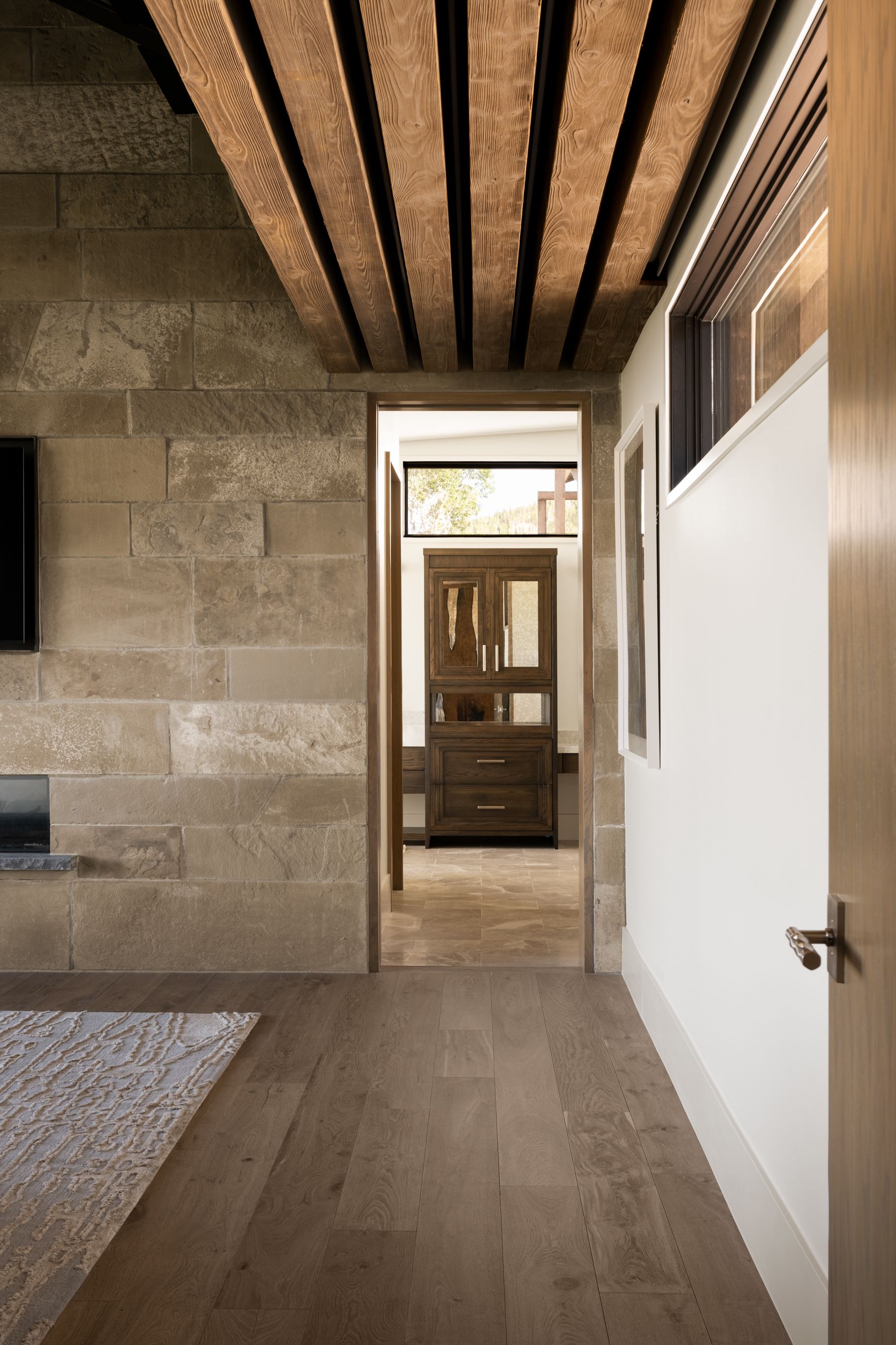 A hallway in a house with a brick wall and wooden floors