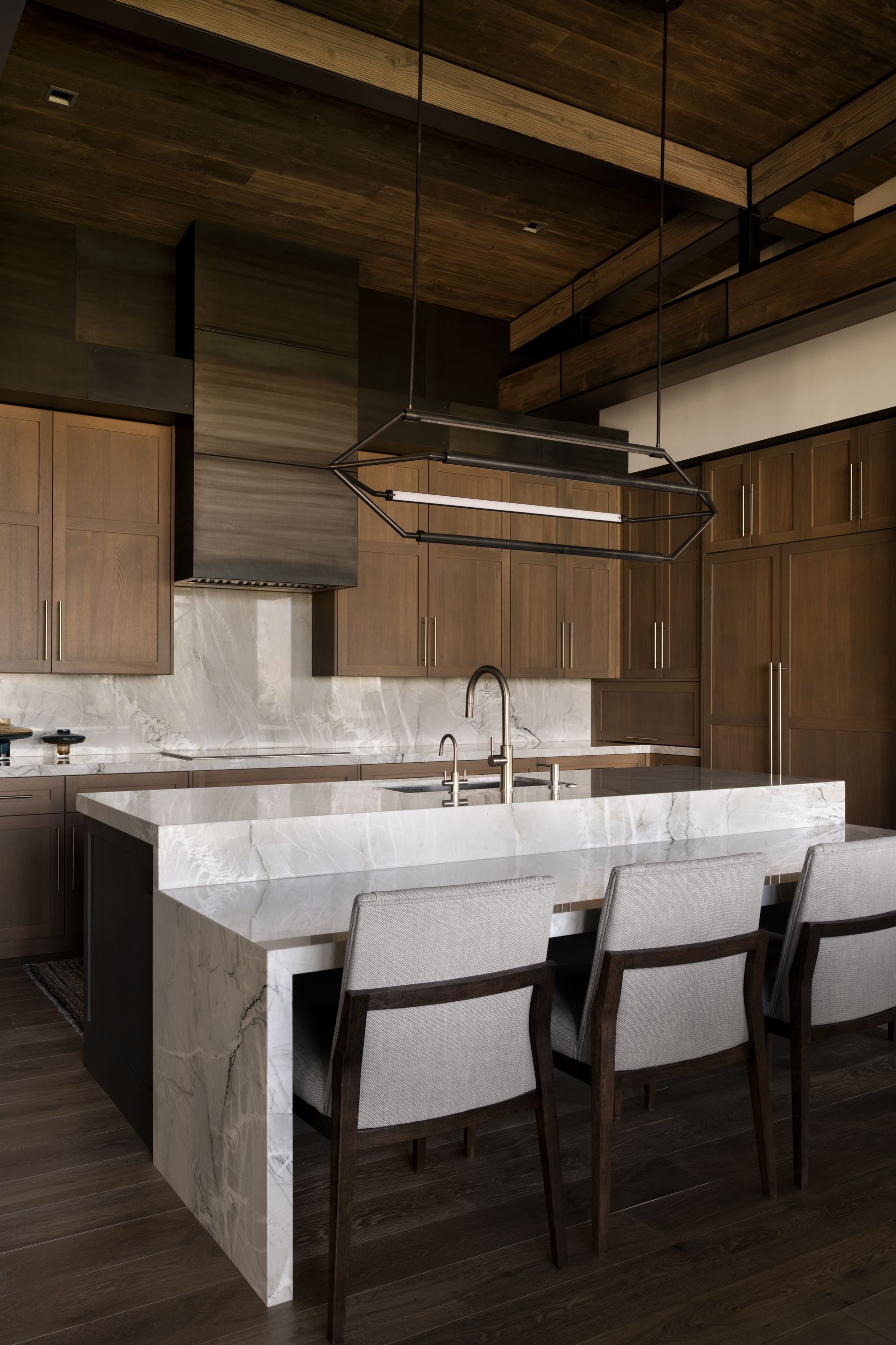 A kitchen with a large island and chairs in it.