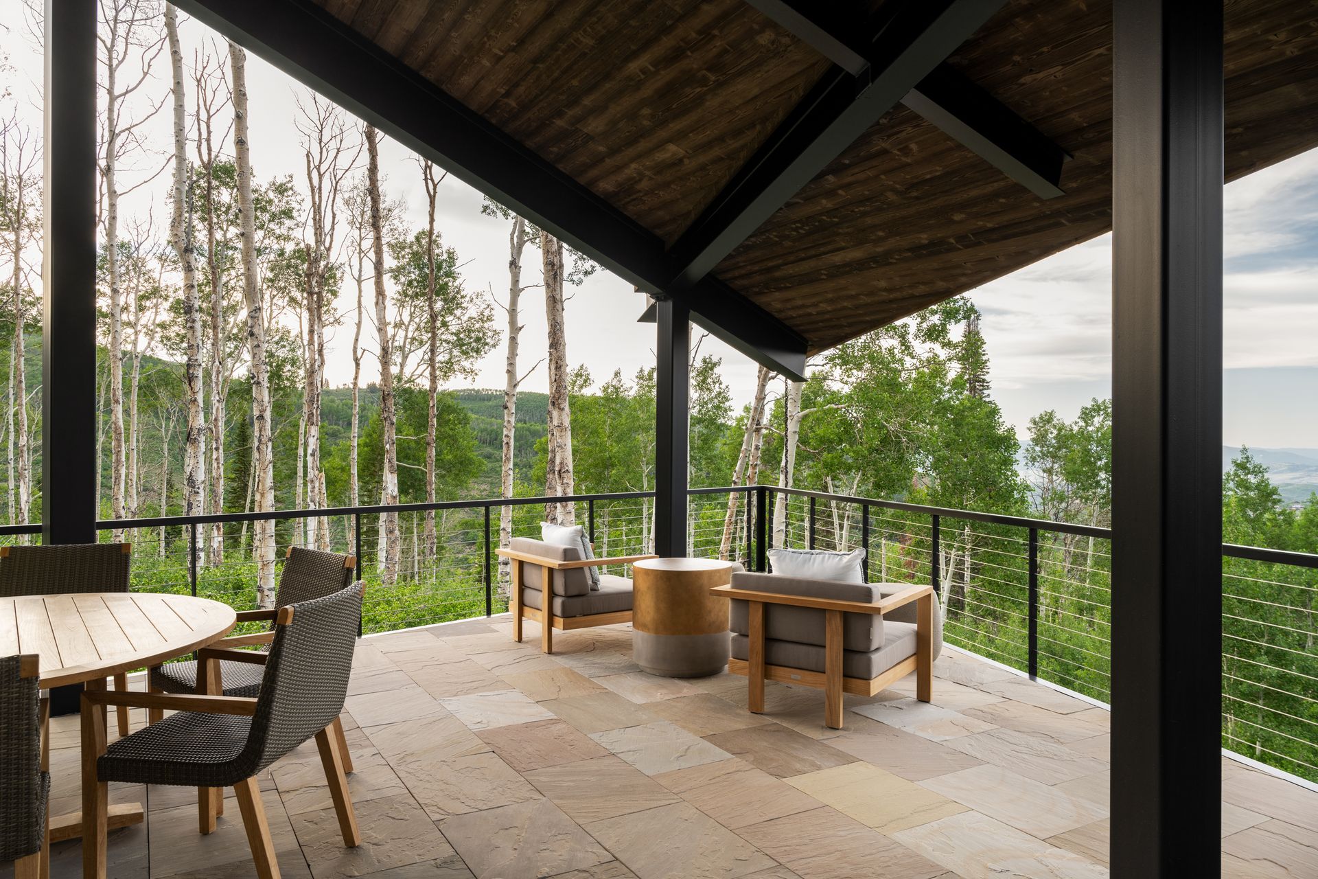 A balcony with a table and chairs overlooking a forest.