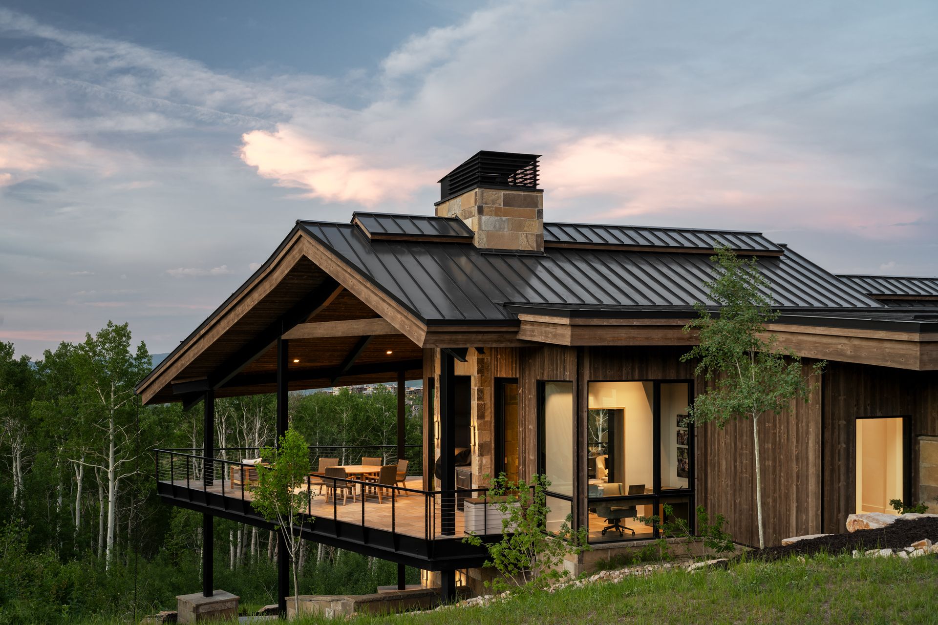 A large wooden house with a metal roof is sitting on top of a hill.