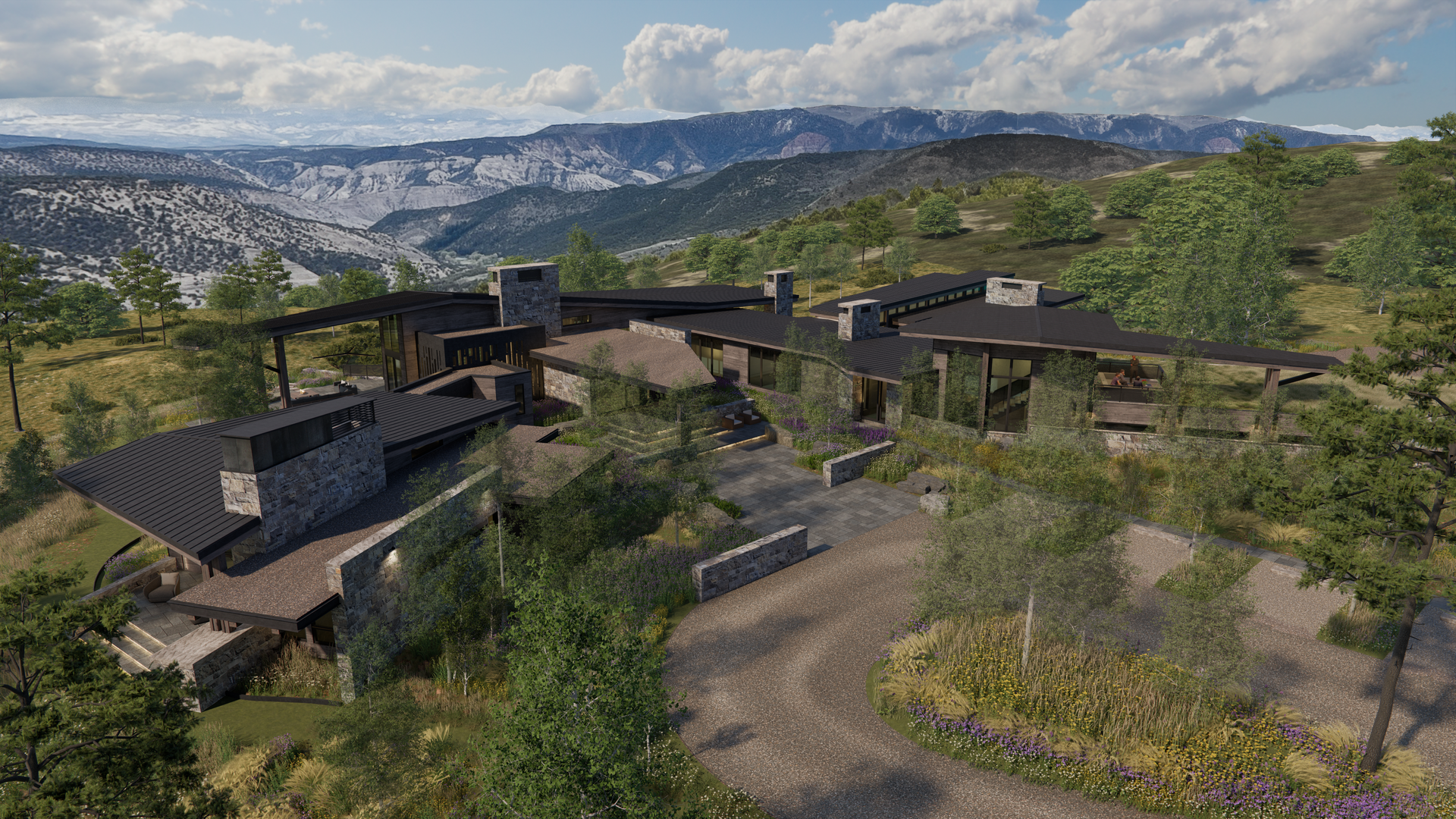 An aerial view of a large house in the middle of a lush green field with mountains in the background.