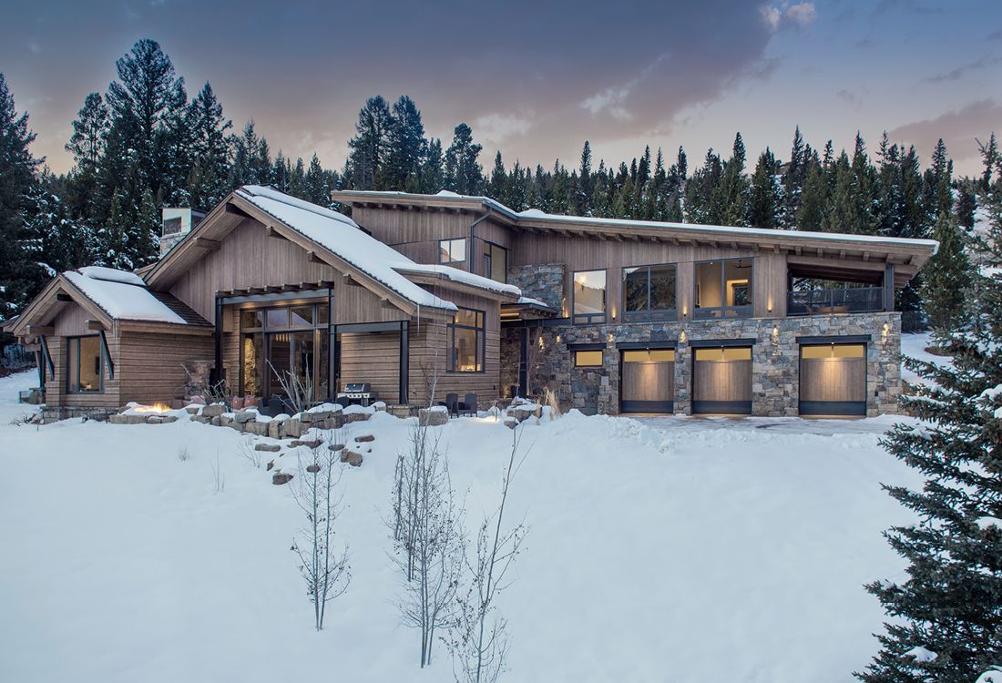 A large house is sitting in the middle of a snow covered field.