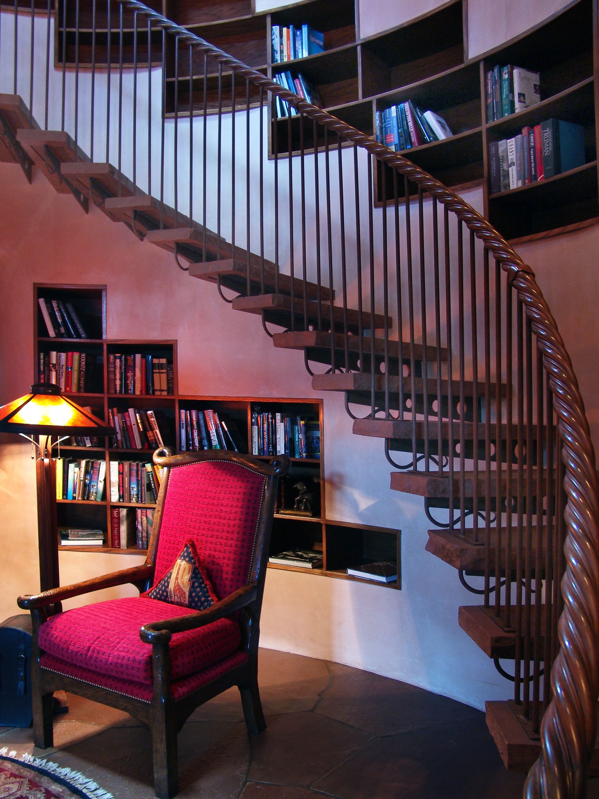 A red chair sits in front of a spiral staircase