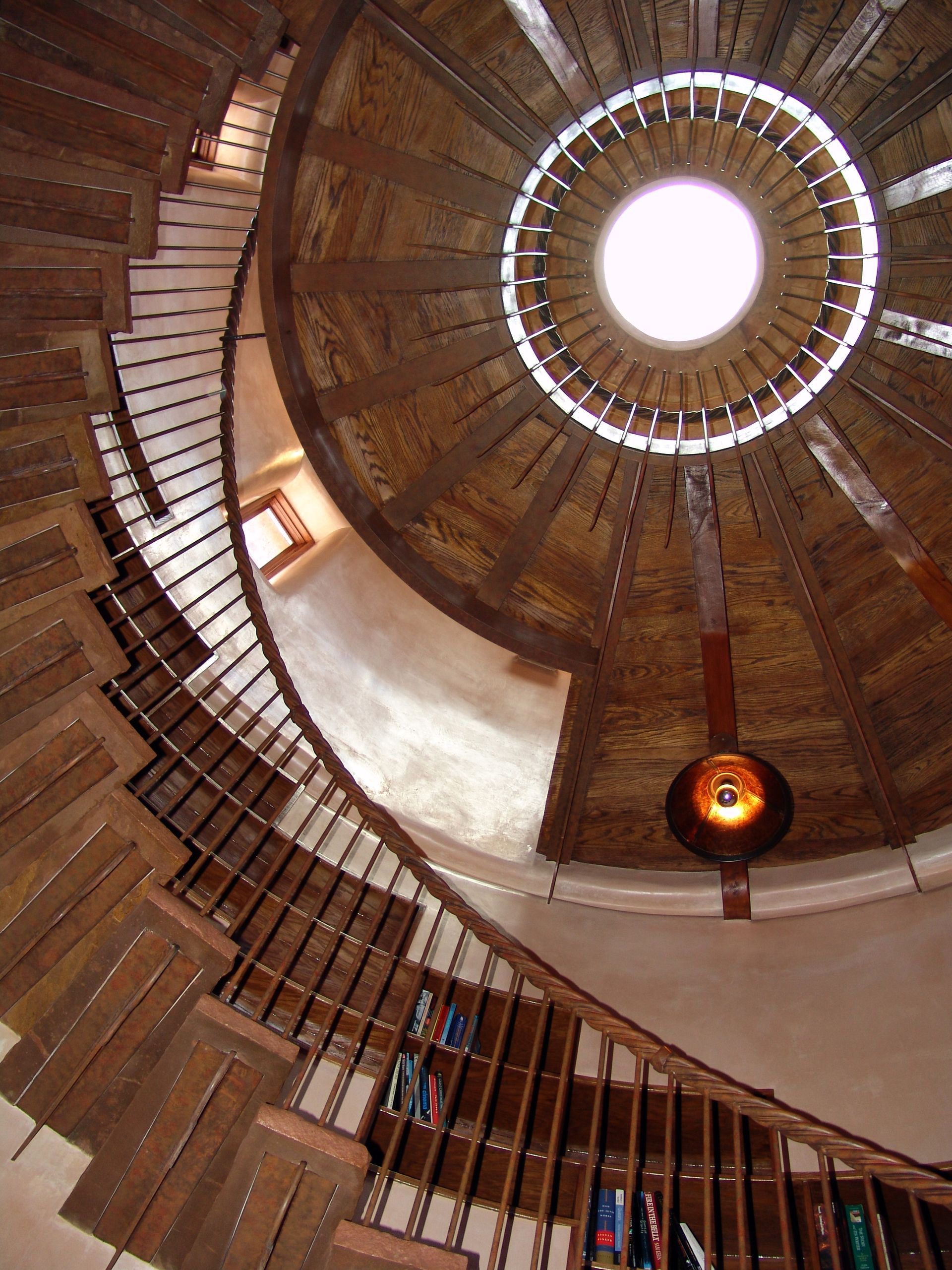 Looking up at a spiral staircase with a light hanging from the ceiling