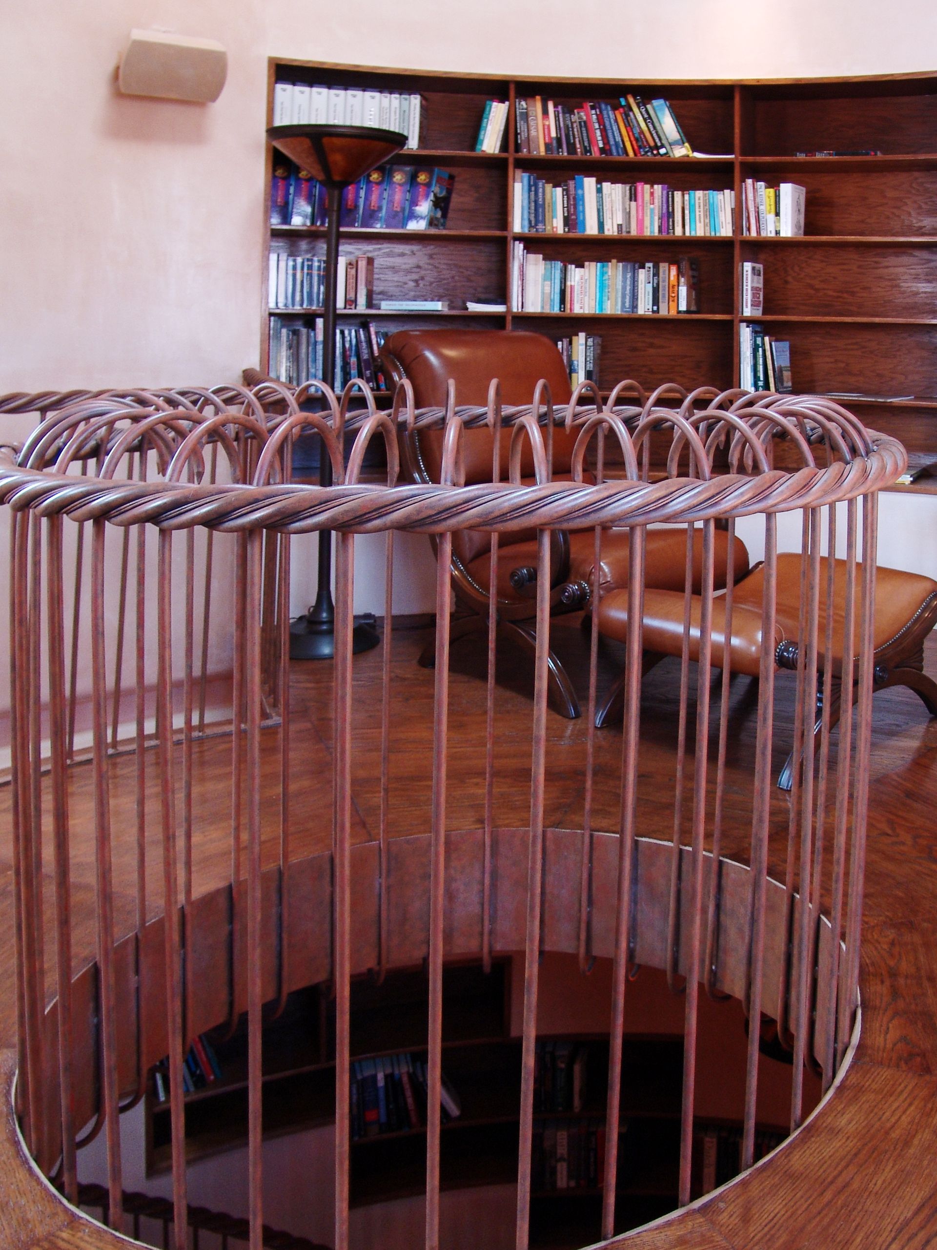 A spiral staircase in a library with a fence around it