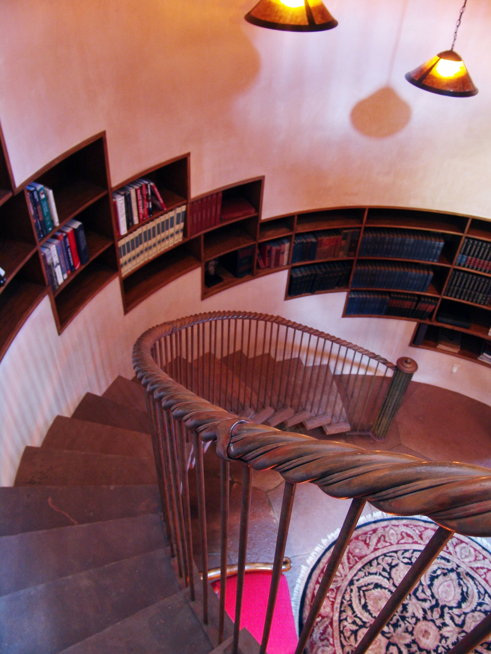 A spiral staircase in a library with shelves full of books